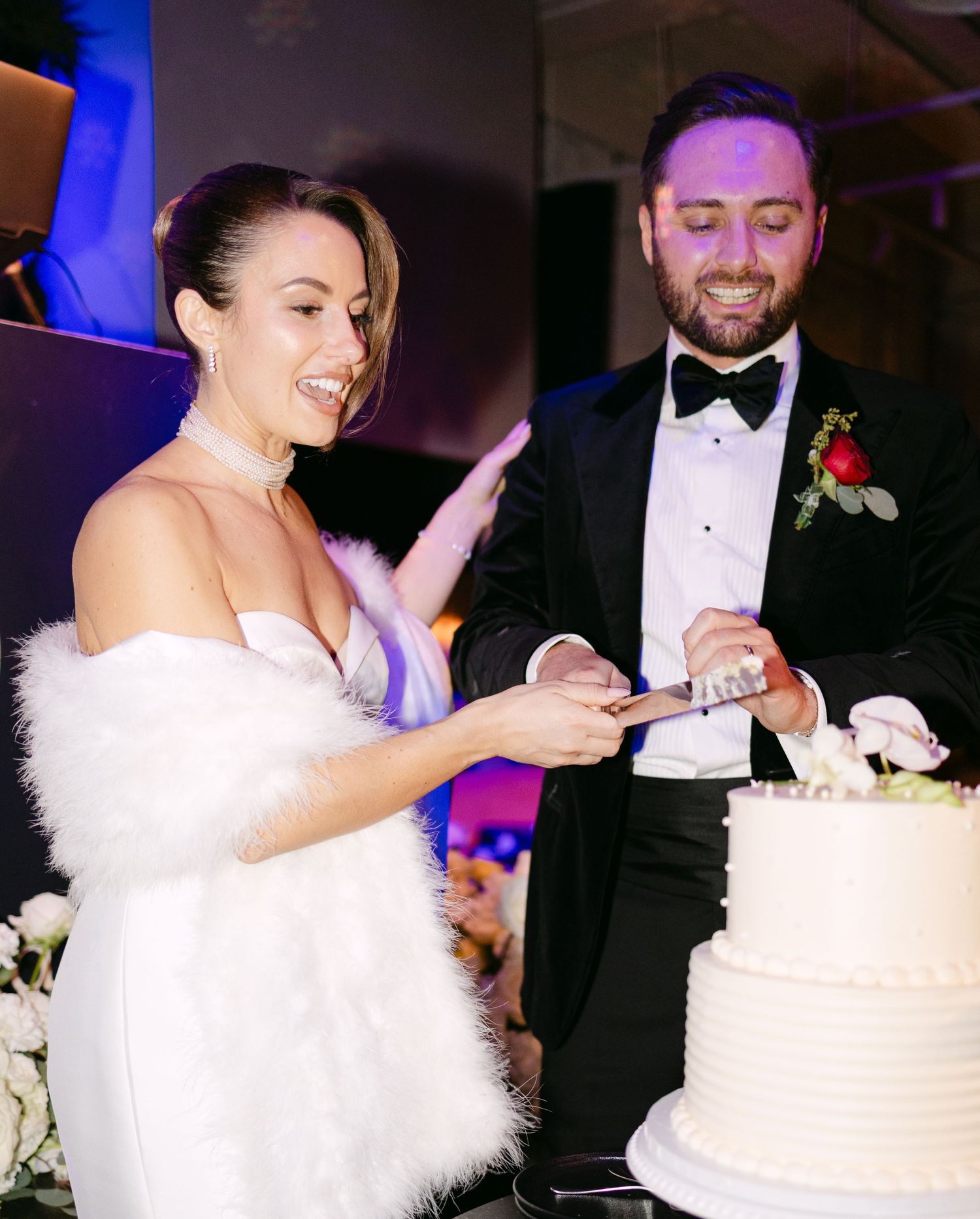 Couple cuts their elegant white wedding cake together during reception celebration.
