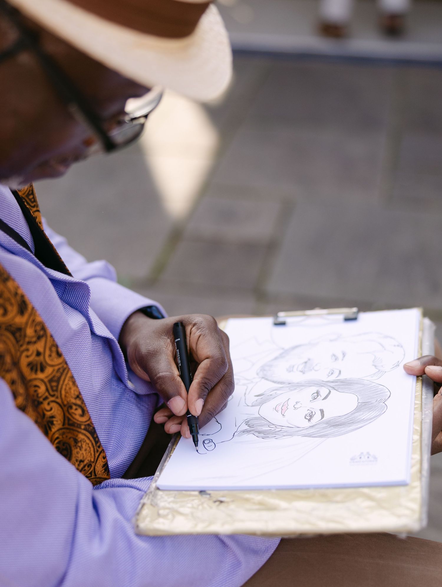 Close-up of hands sketching a portrait in a notebook.