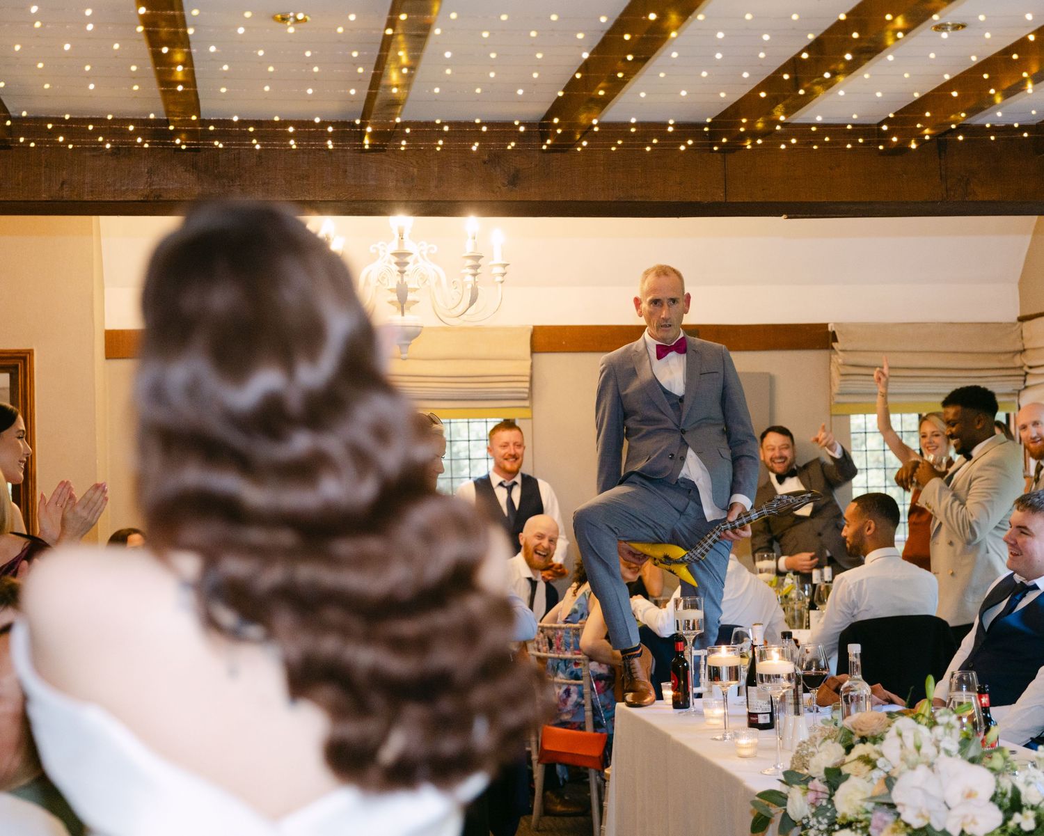 Wedding reception venue with twinkling fairy lights and exposed wooden beams.
