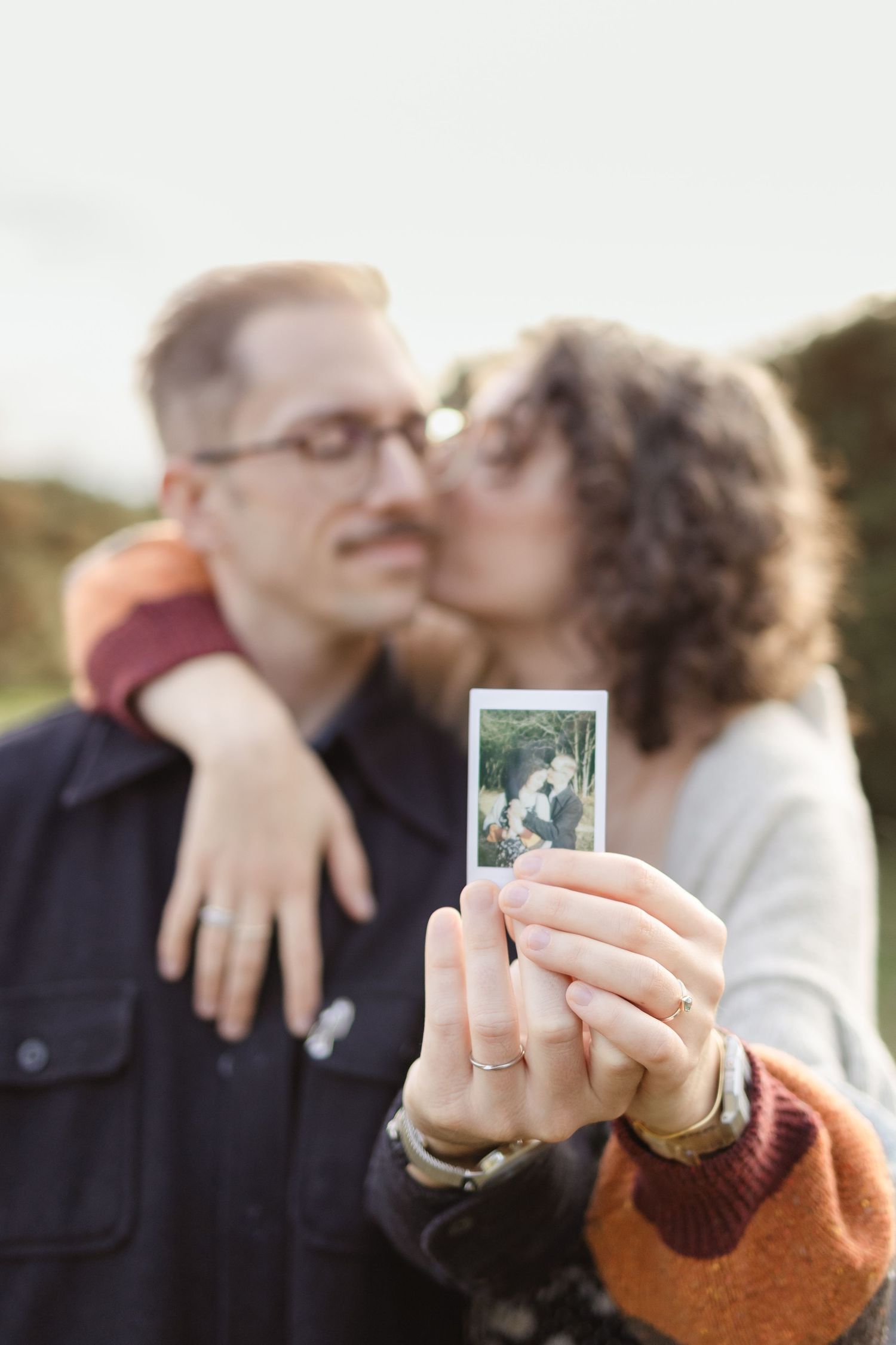 Hand holding a polaroid photo during an outdoor engagement session.
