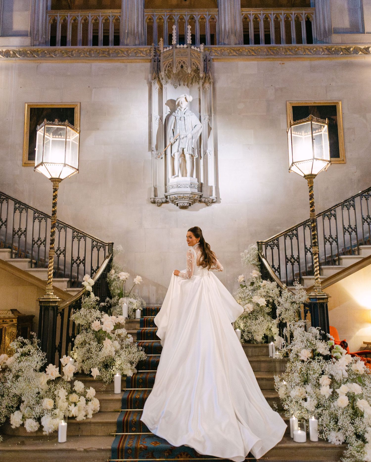 Grand entrance hall decorated with white flowers and illuminated by hanging lanterns for wedding ceremony.