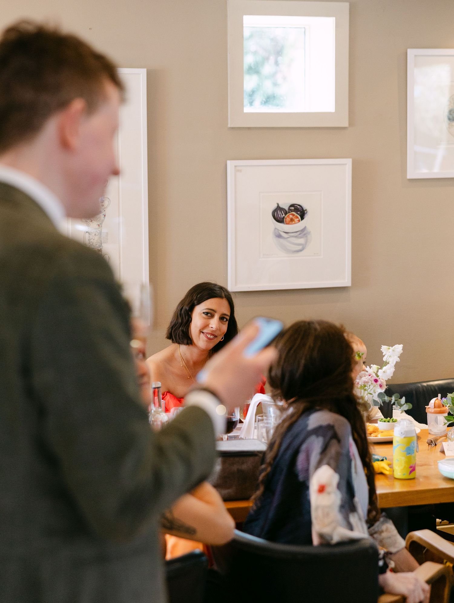 A lively indoor gathering shows people seated at tables enjoying a casual meal together.