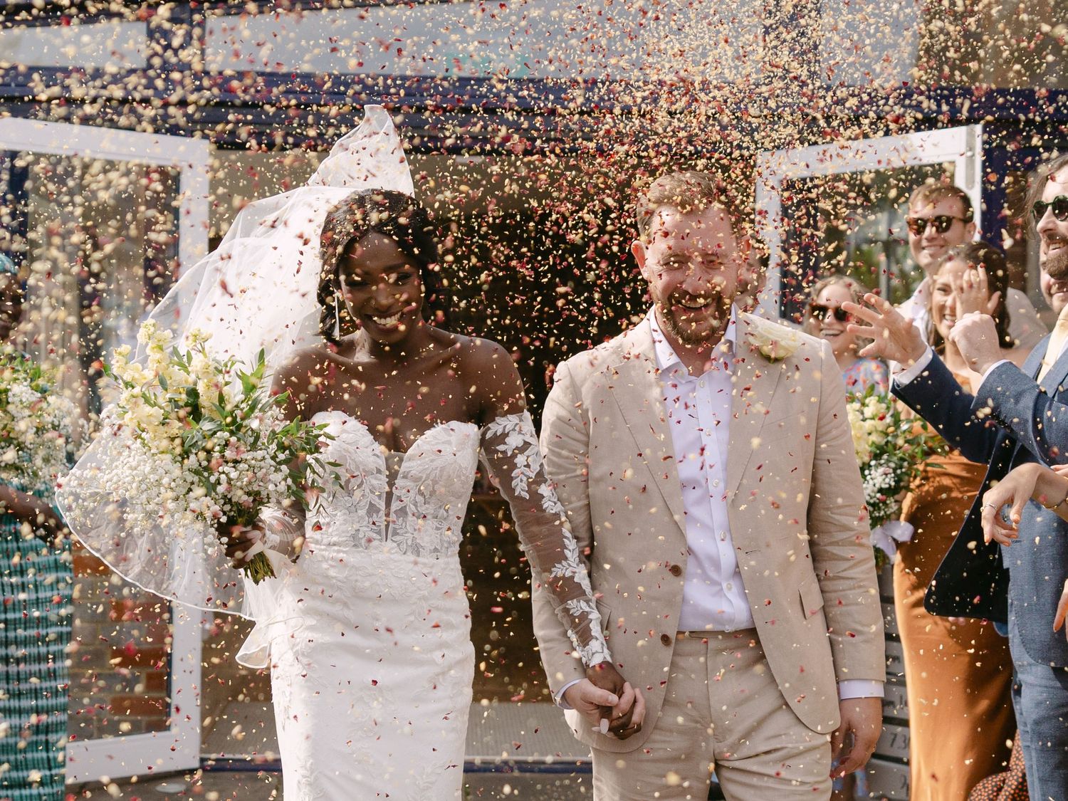 Newlyweds walking through a shower of confetti during their wedding exit.