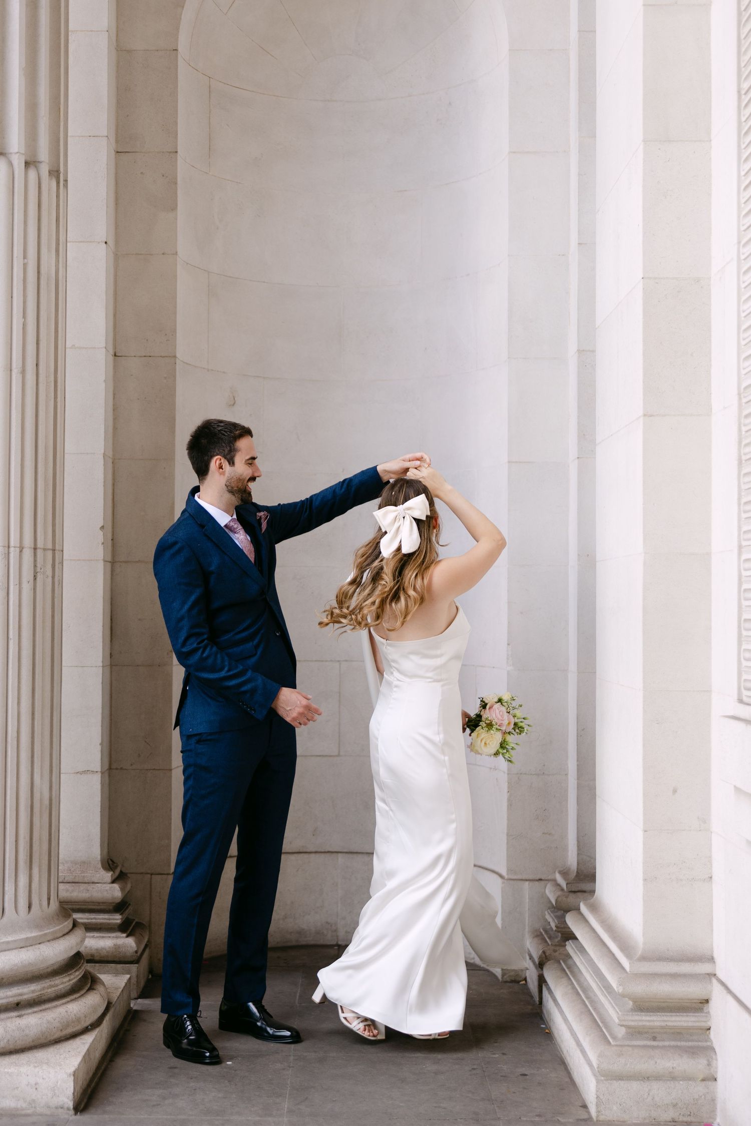 Newlyweds twirling during wedding portraits outside Old Marylebone Town Hall London