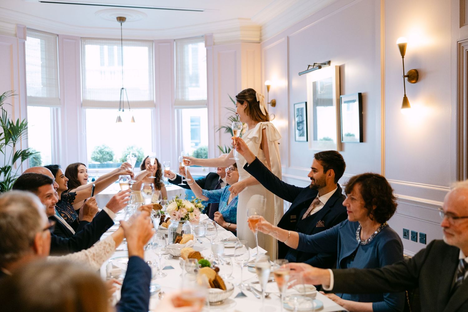 Bride giving toast at long wedding table during intimate lunch reception at The Kensington Hotel