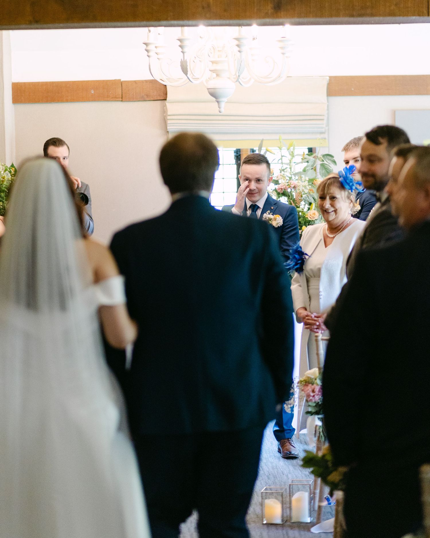 Wedding ceremony in progress with guests standing in a bright indoor venue.