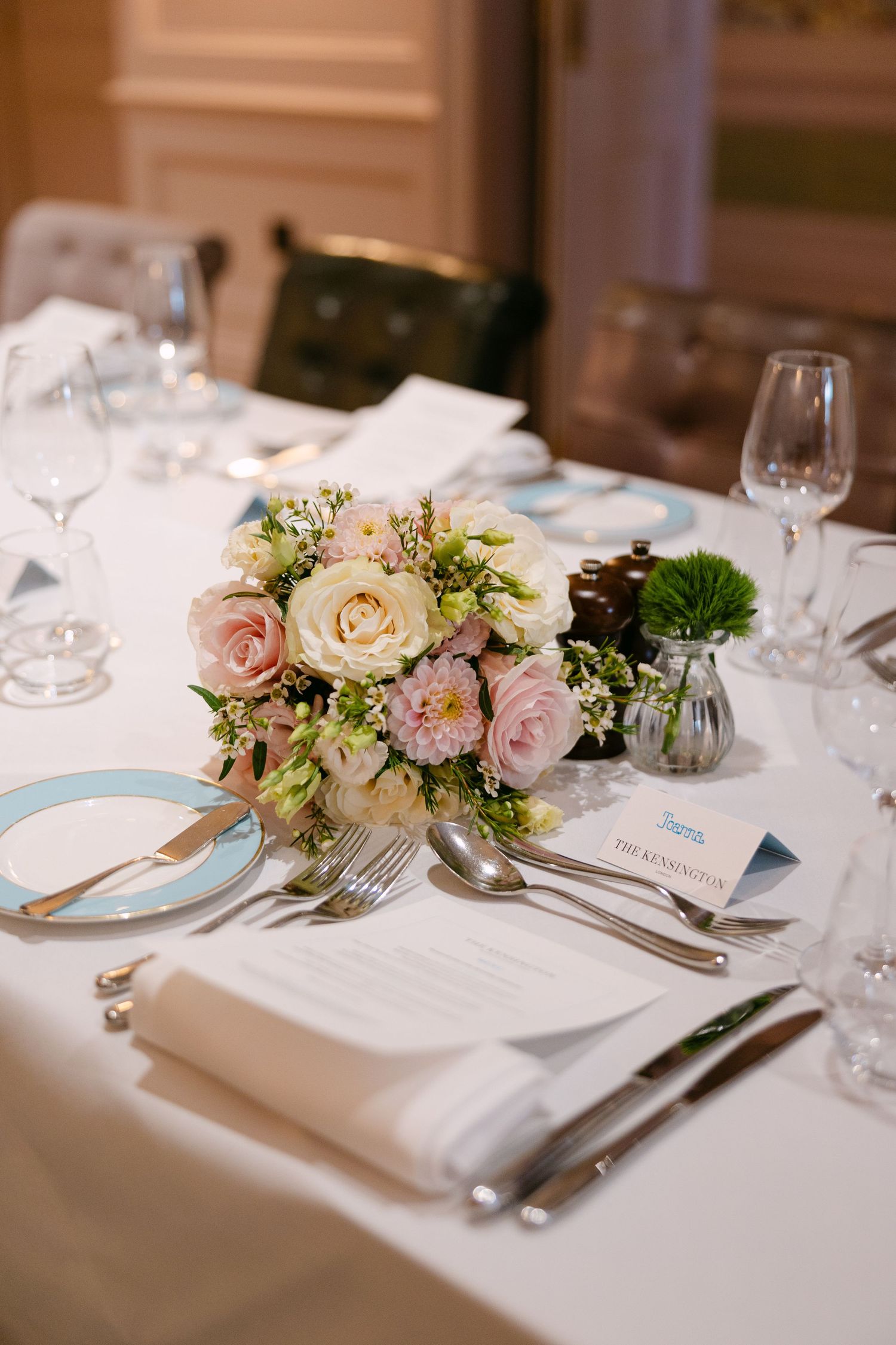 An elegant wedding table setting with pink and white roses, fine china, and crystal glassware at The Kensington Hotel.