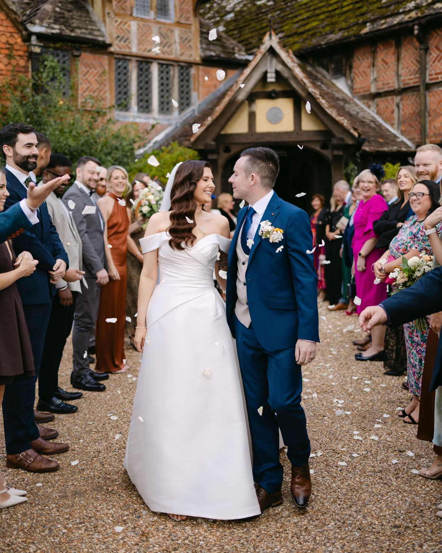 Wedding celebration with confetti being thrown outside a Tudor-style church.