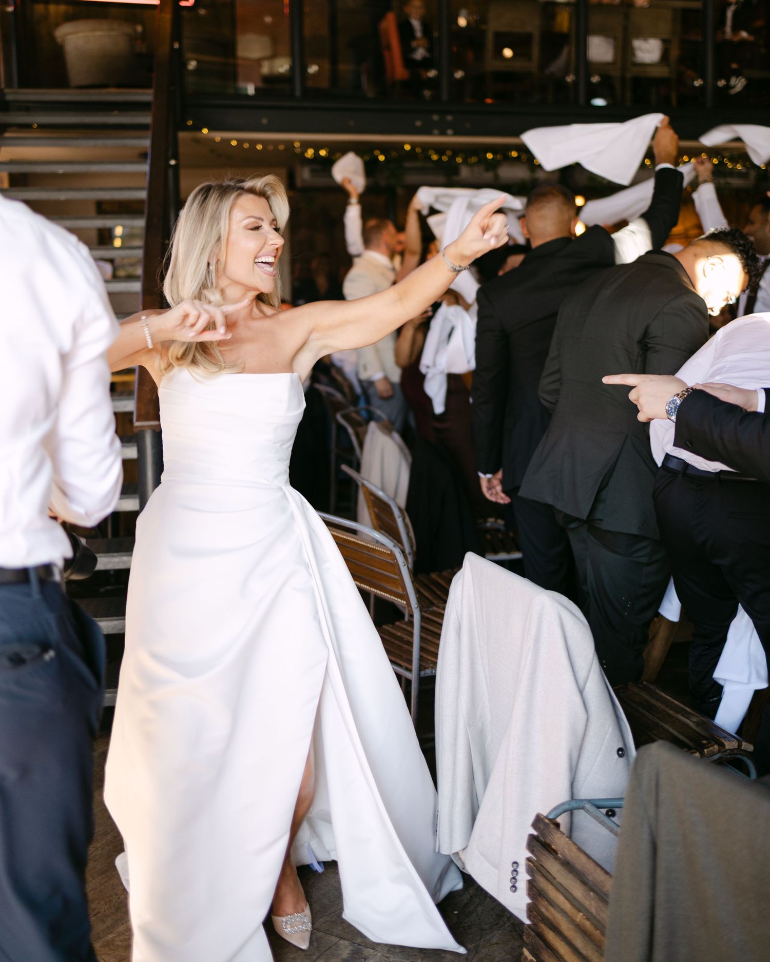 Wedding reception guests dance and celebrate in elegant indoor venue.