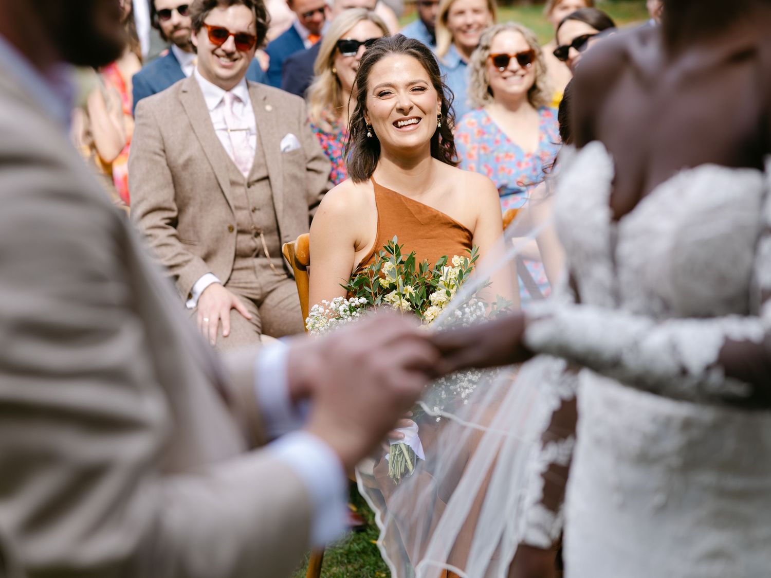 Wedding guests smiling and celebrating during an outdoor garden ceremony.