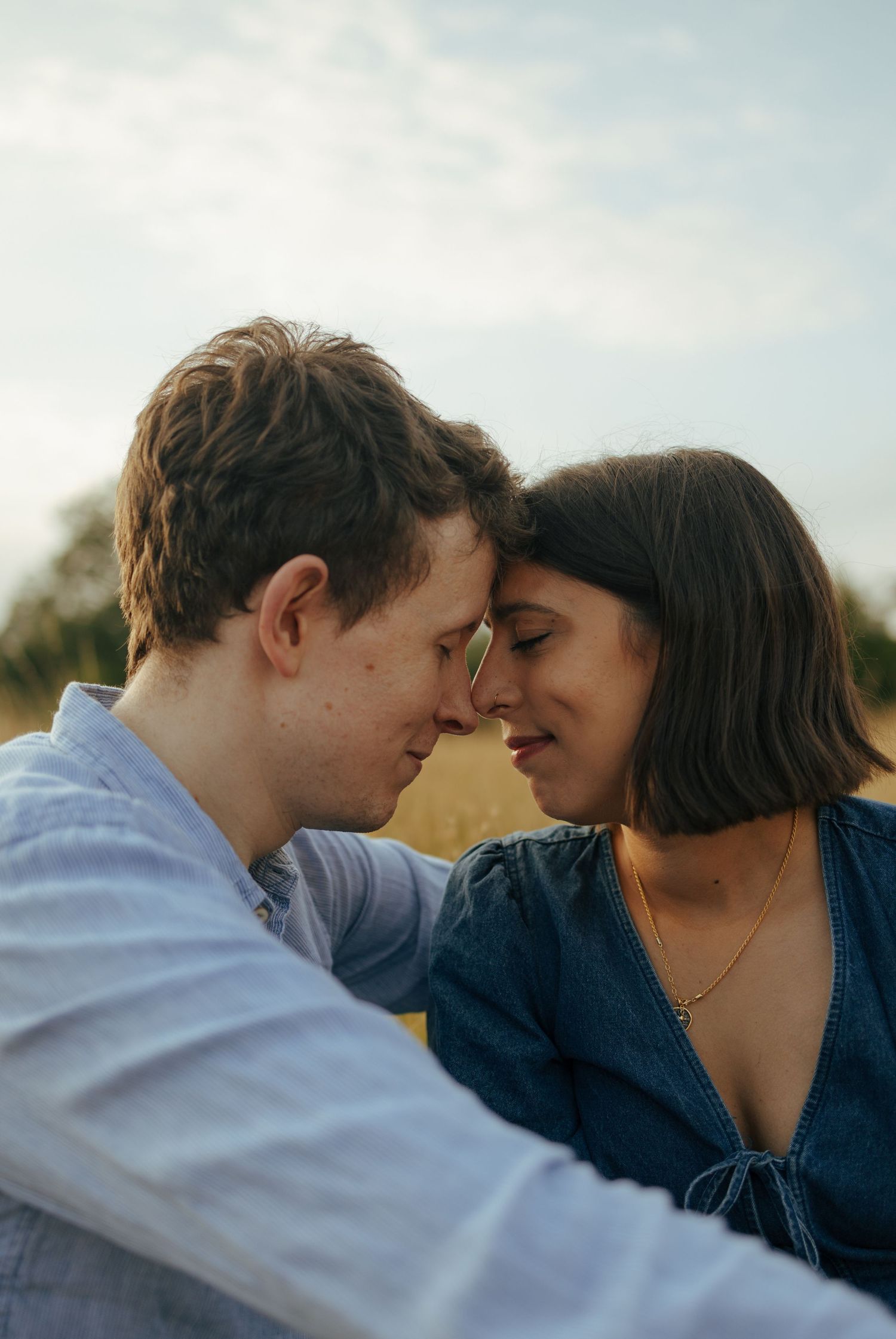 A couple shares tender moments in a sunlit field with tall grass.