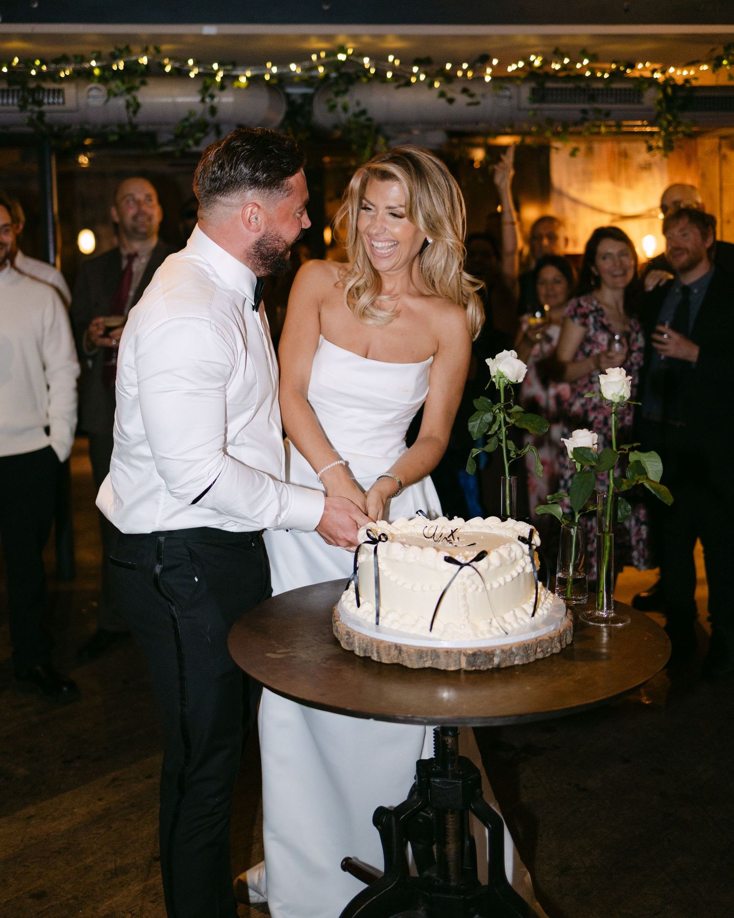 Newlyweds sharing a joyful moment while cutting their white wedding cake at their reception.