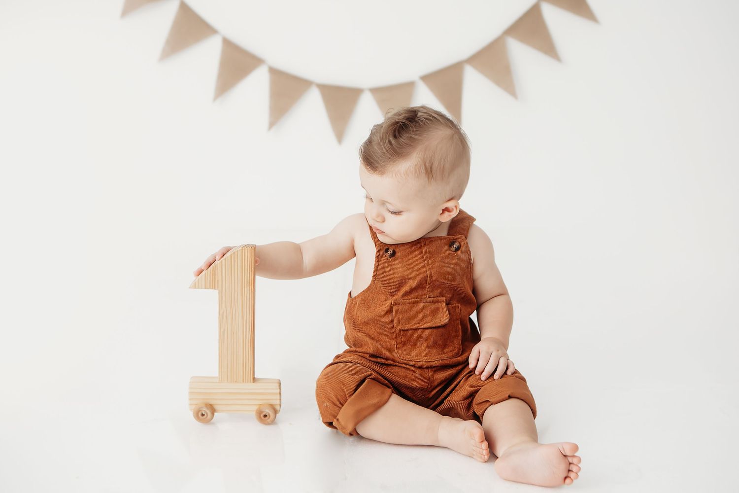 White bunting flags and wooden number one decorate a minimalist photography setup.