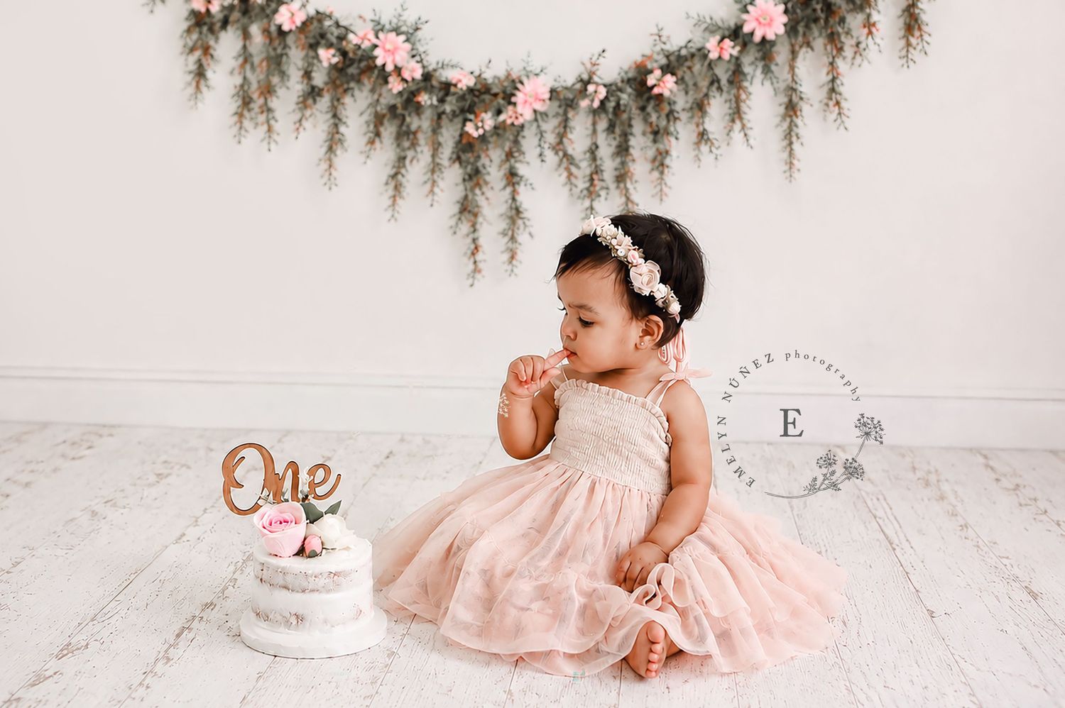 Baby girl in pink dress sits beside a \