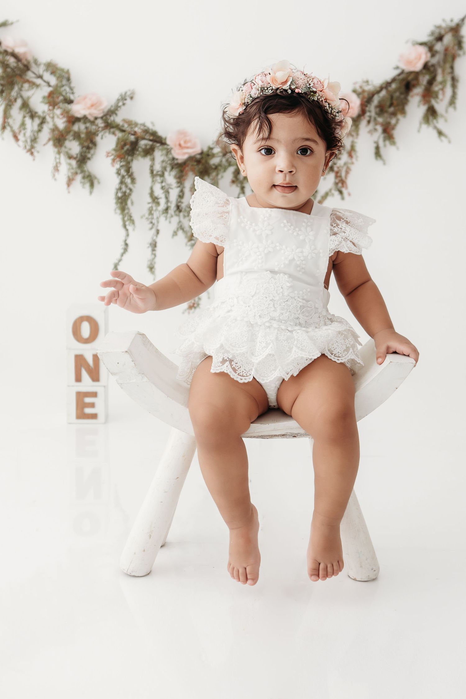 White lace outfit and floral decorations arranged for milestone photography.