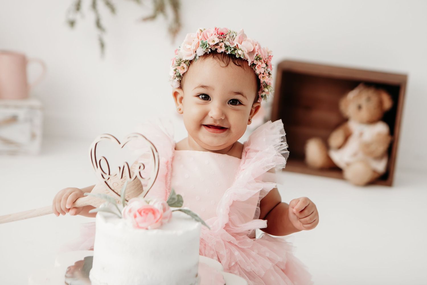 A delicate pink and white cake with floral decorations sits on a white surface during a celebration.