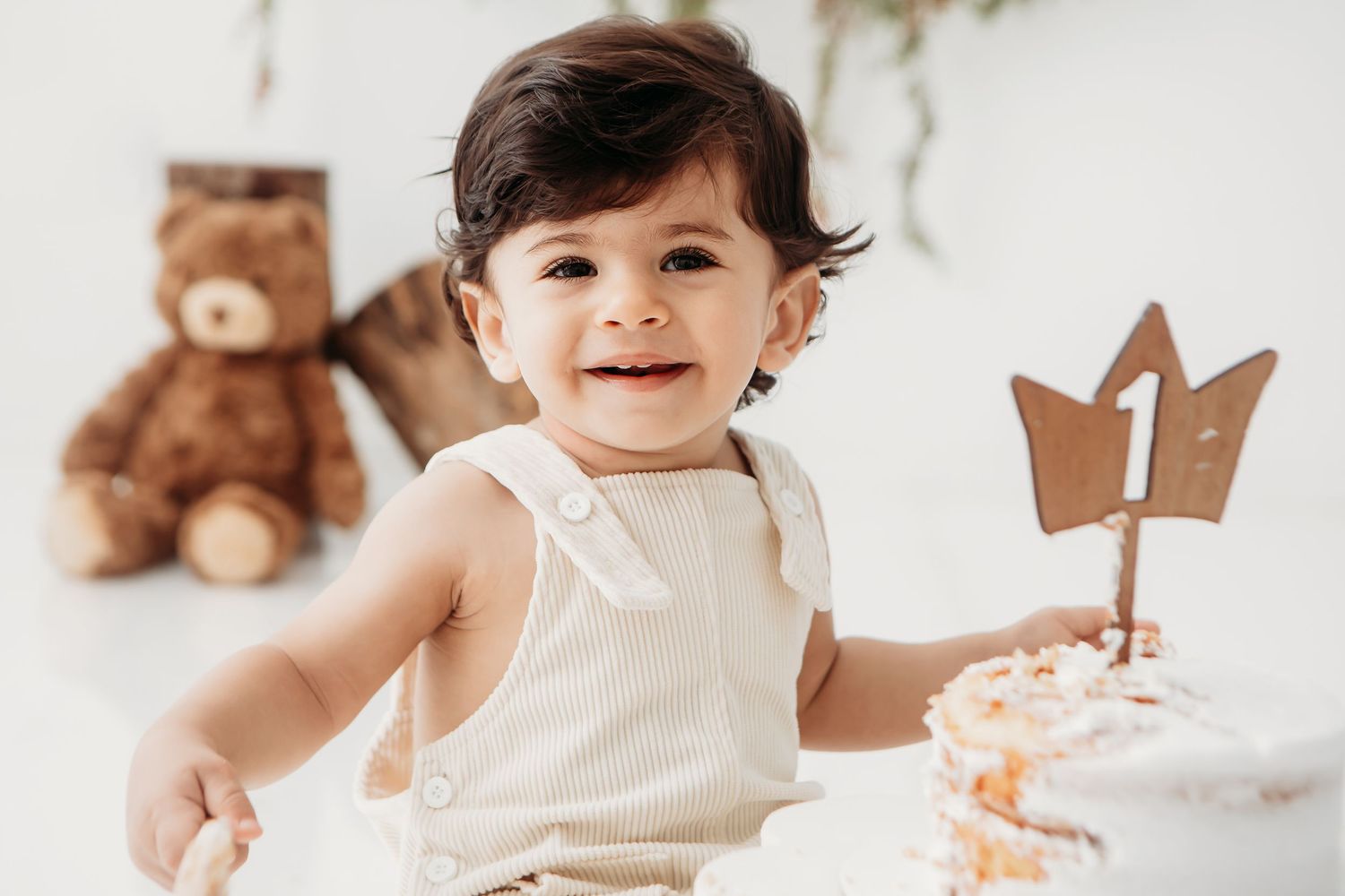 Baby in cream outfit reaches for decorative props during milestone photo session.
