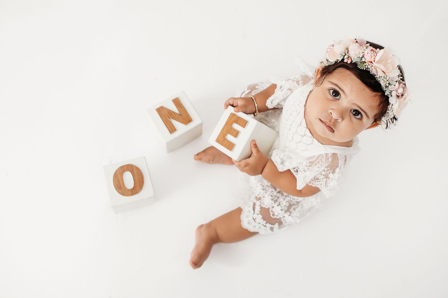 Wooden letters and decorative elements arranged on white background for milestone photography.