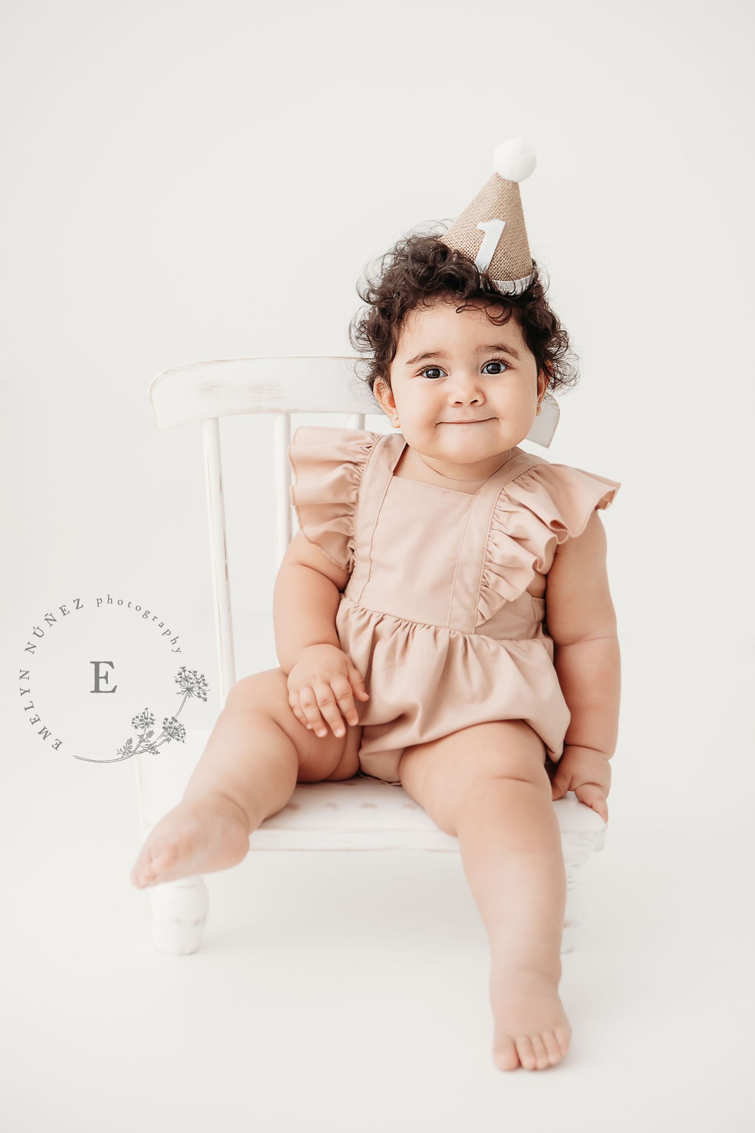 A baby in a pink ruffled romper poses on a white backdrop in a series of sweet milestone portraits.