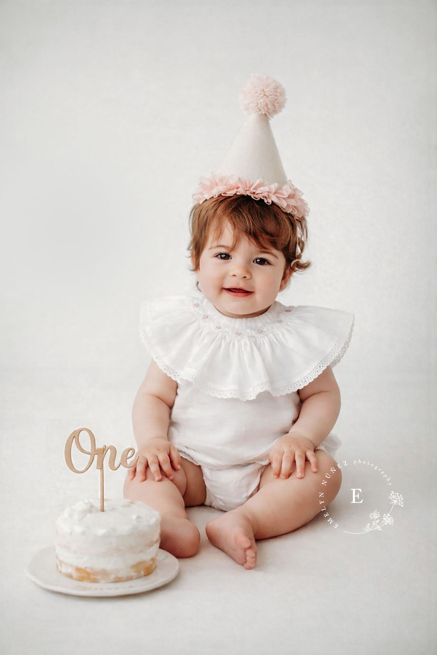 A series of milestone photos showing a baby in white ruffled outfit with a pink bow and birthday cake against a light backdrop.
