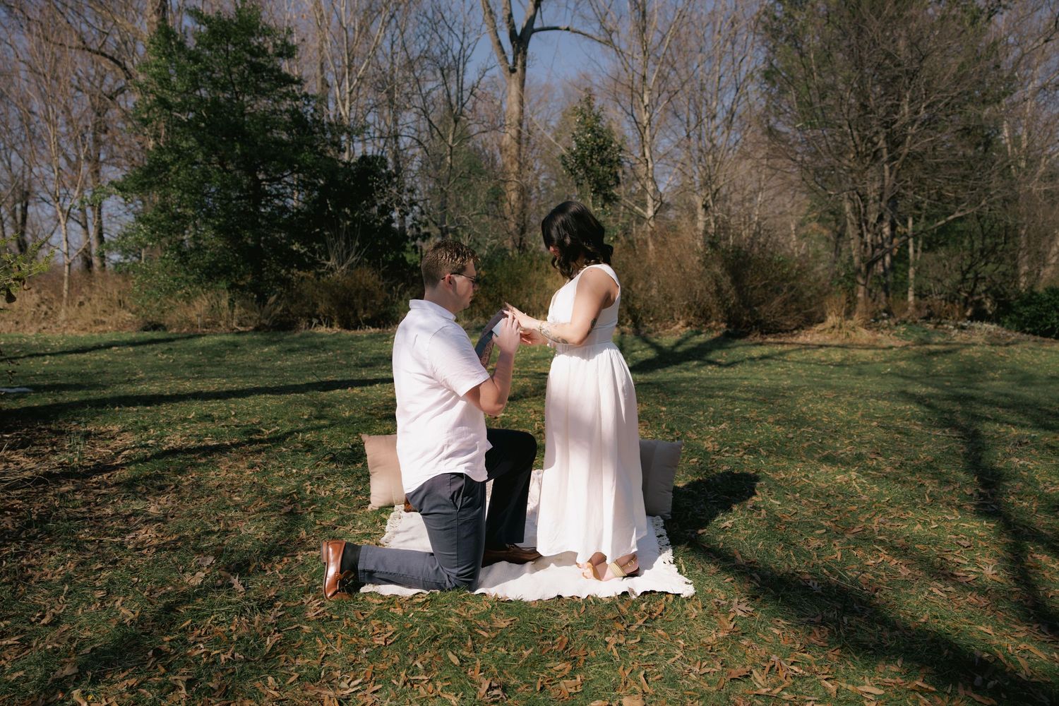 Couple in the DMV during outdoor proposal session, groom kneeling as bride reacts with joy, captured by Rhen Marie Photography