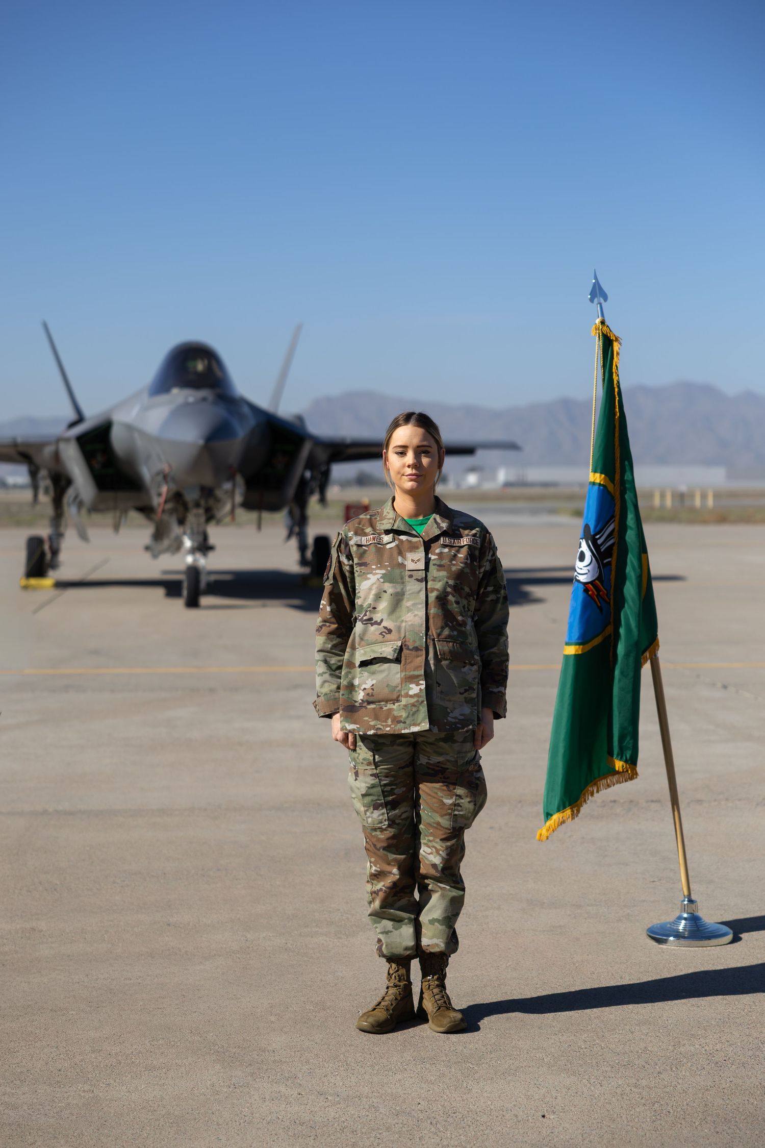 Female service member standing proudly in uniform next to military F-15 jet, photographed by Rhen Marie Photograph
