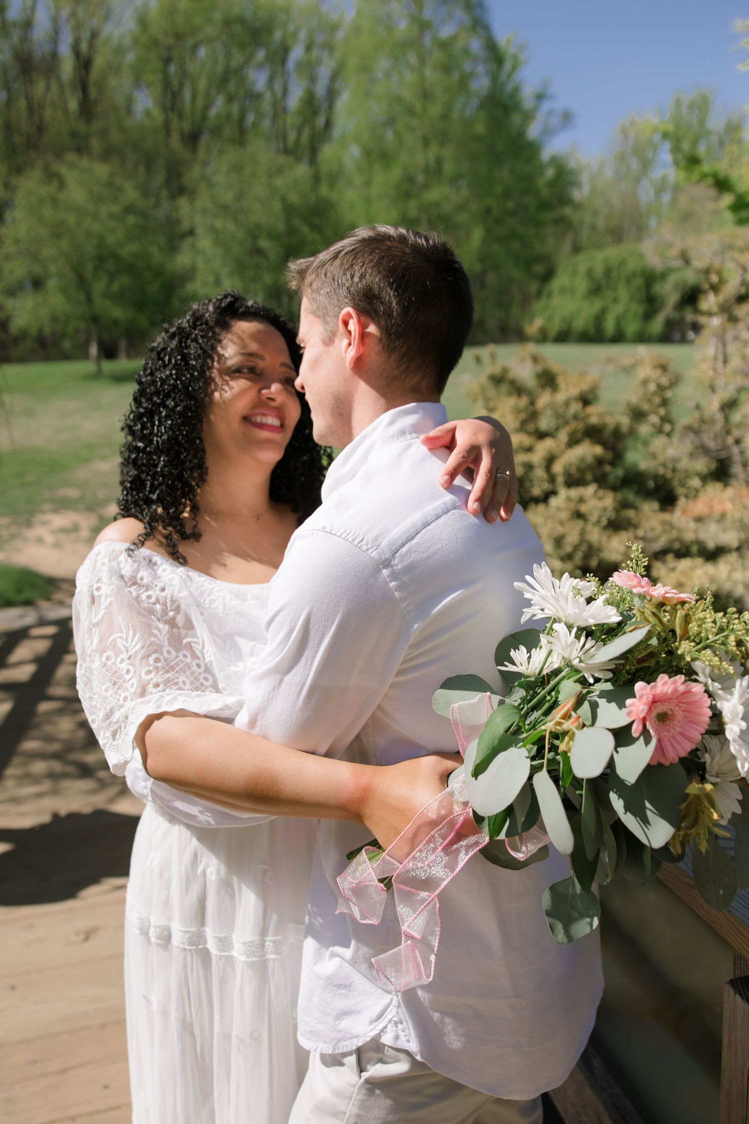 Couple embracing during an outdoor wedding session in the DMV, bride holding bouquet, captured by Rhen Marie Photography