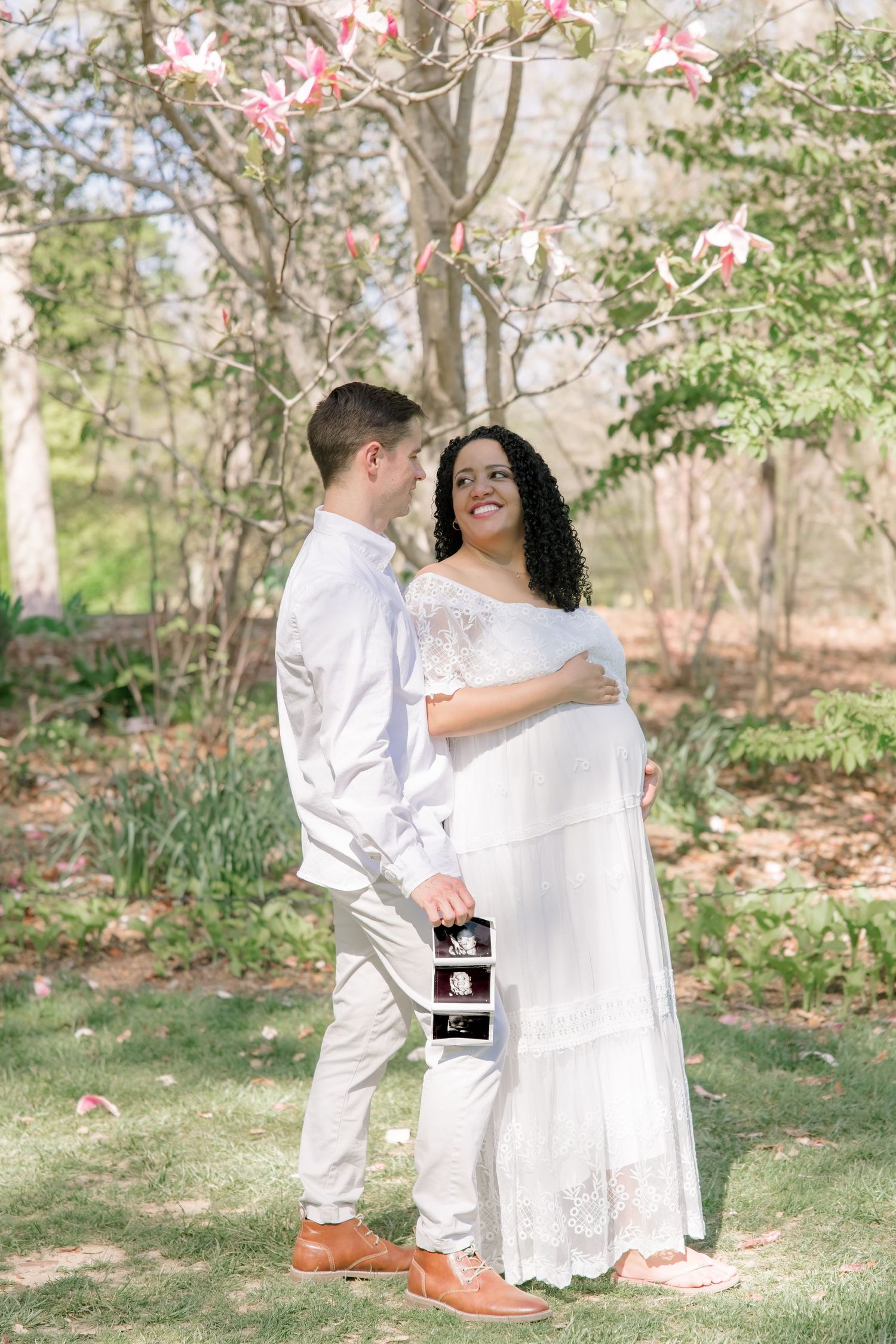 Couple standing together outdoors in DMV park, showcasing ultrasound photos and maternity, Rhen Marie Photography