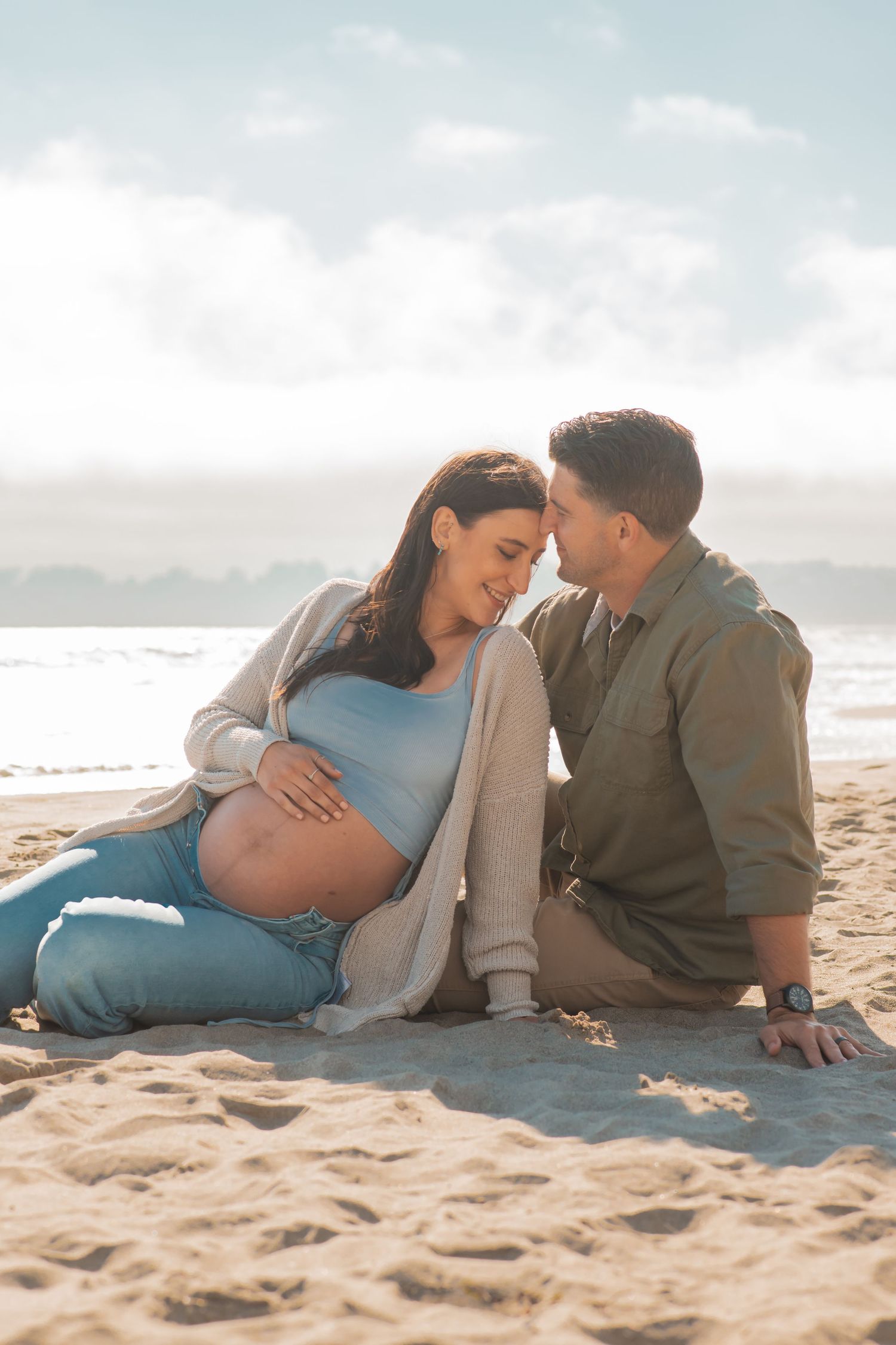 Romantic scene of an expecting couple relaxing on a sandy beach during sunset.
