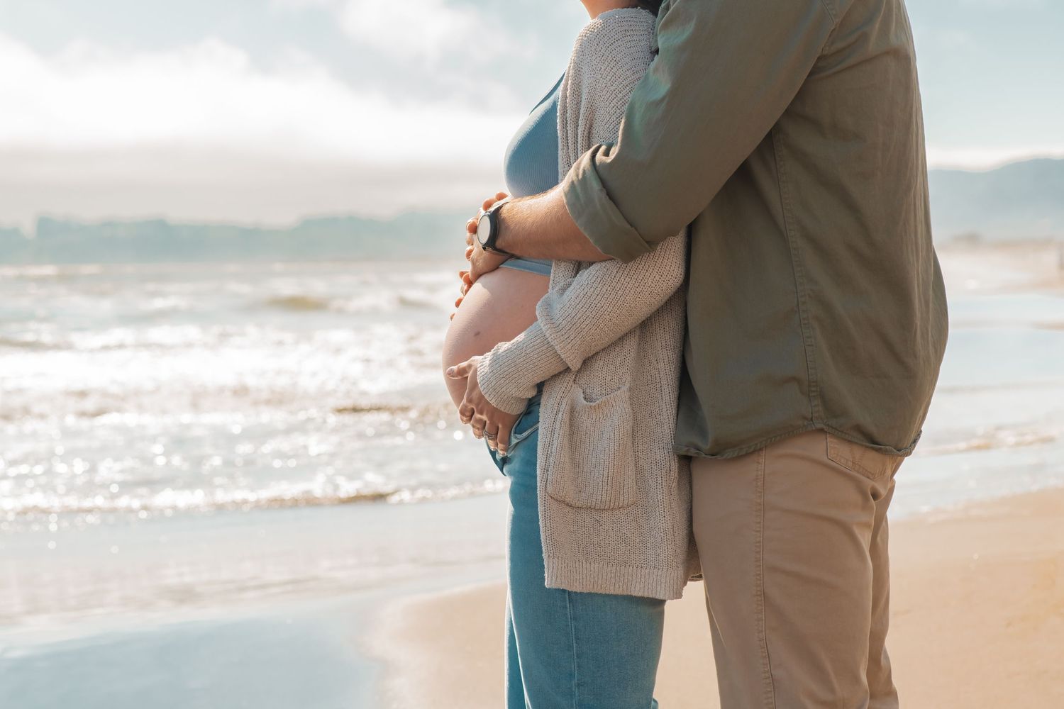 An intimate beachside moment captured as a couple embraces near the ocean waves.