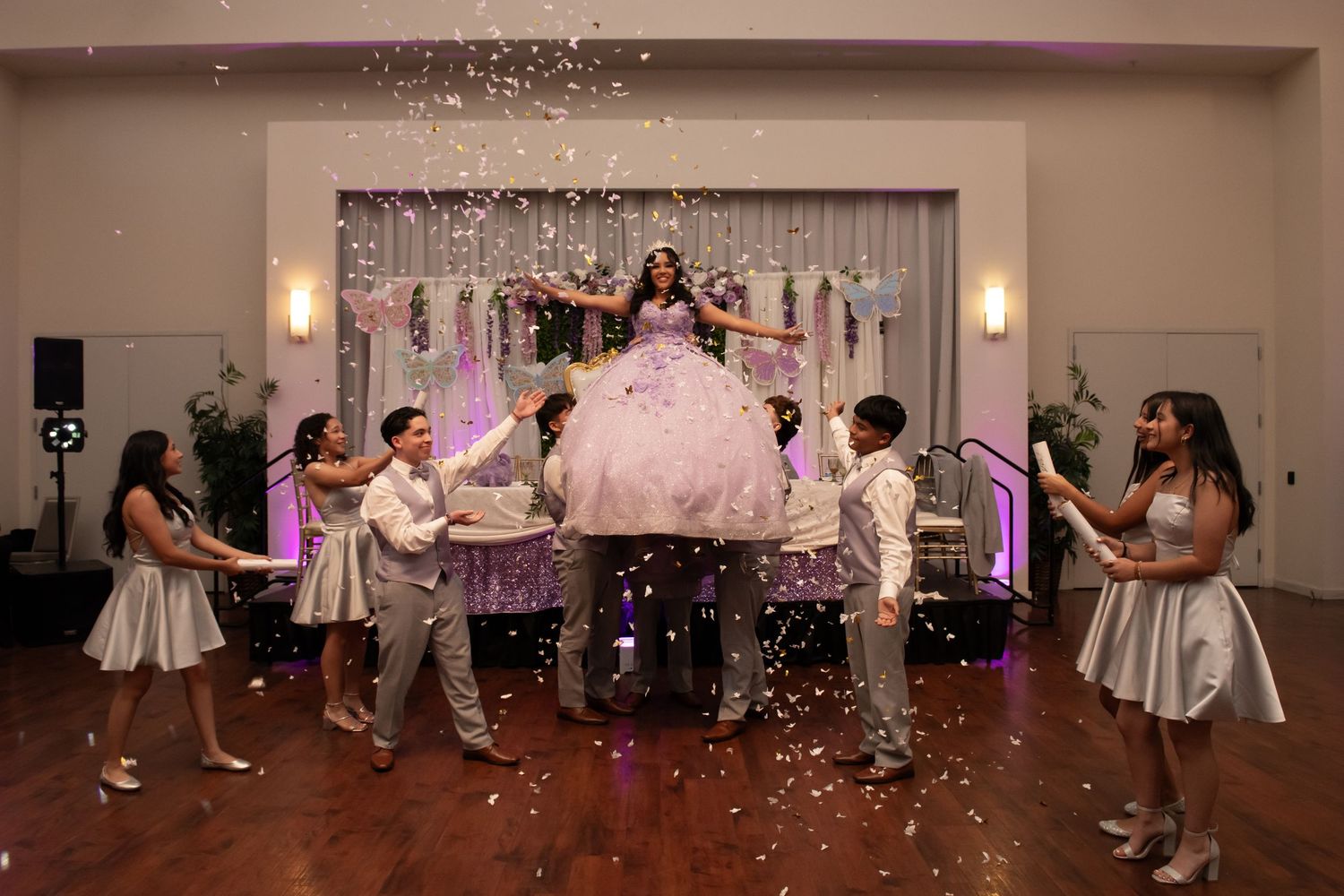 A panoramic view of wedding guests dancing and celebrating in a banquet hall with confetti falling from above.