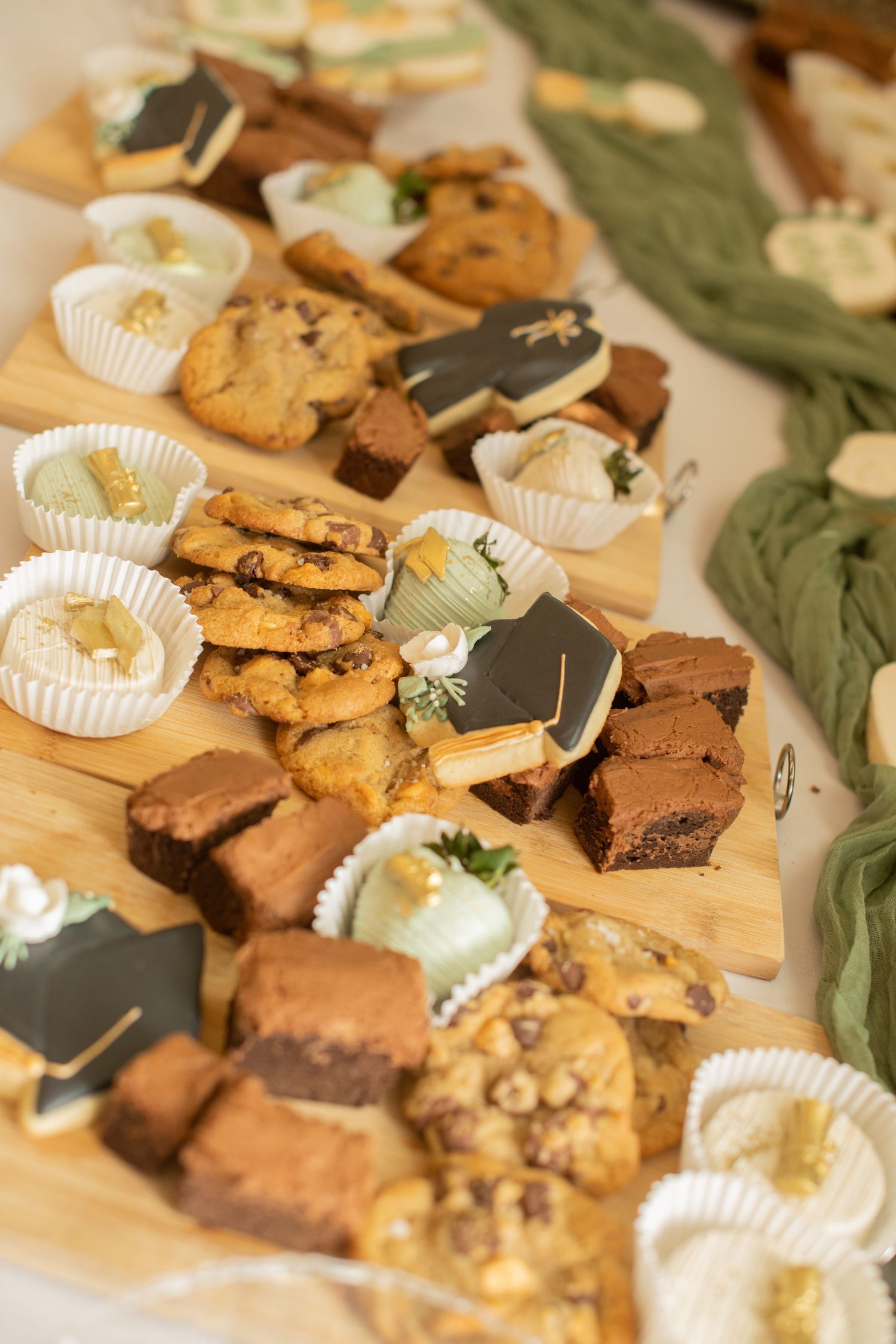 A dessert table display featuring an assortment of cookies, brownies, and chocolate-dipped treats arranged on wooden boards.