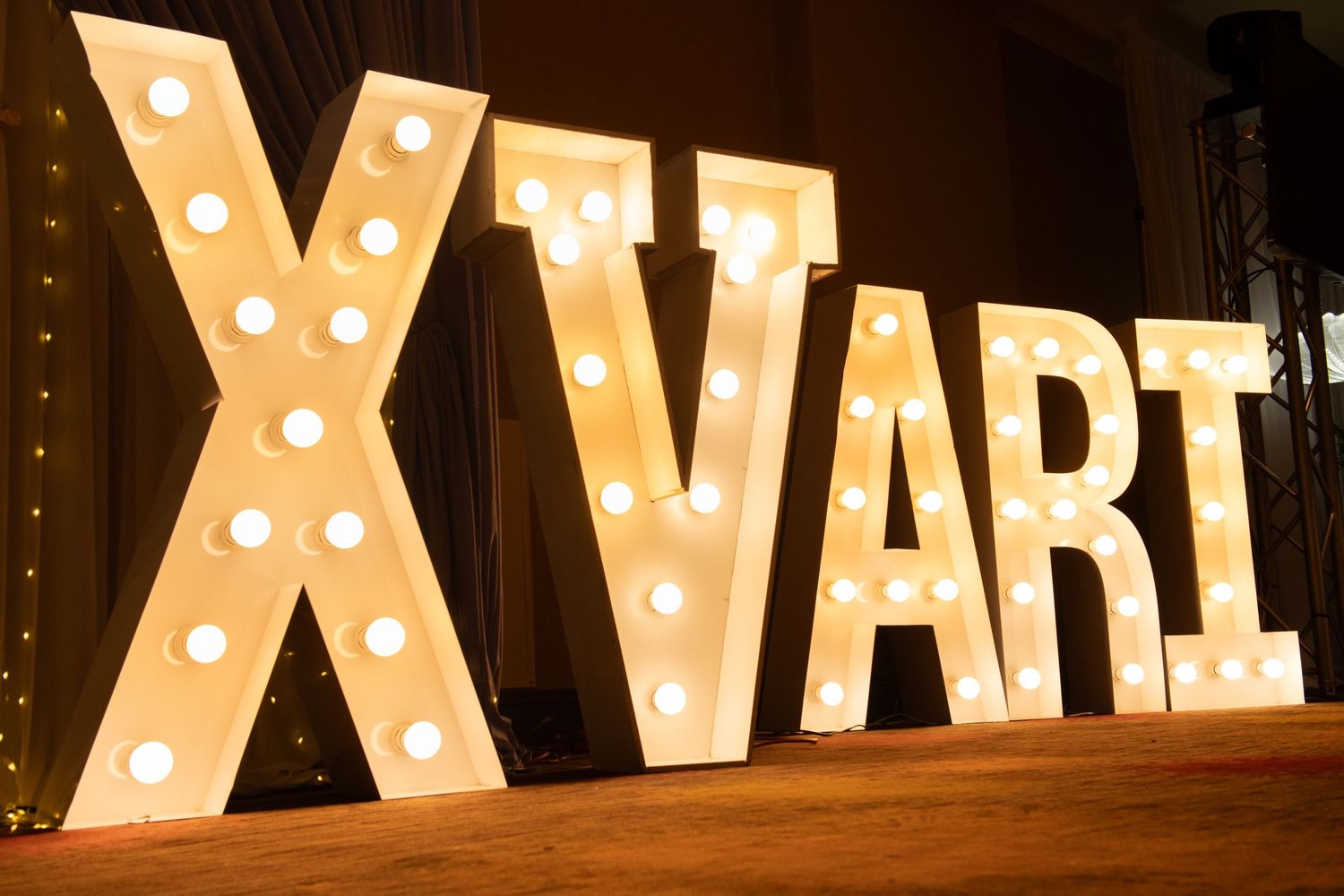 A row of large illuminated marquee letters spelling out words in warm glowing lights against a dark background.