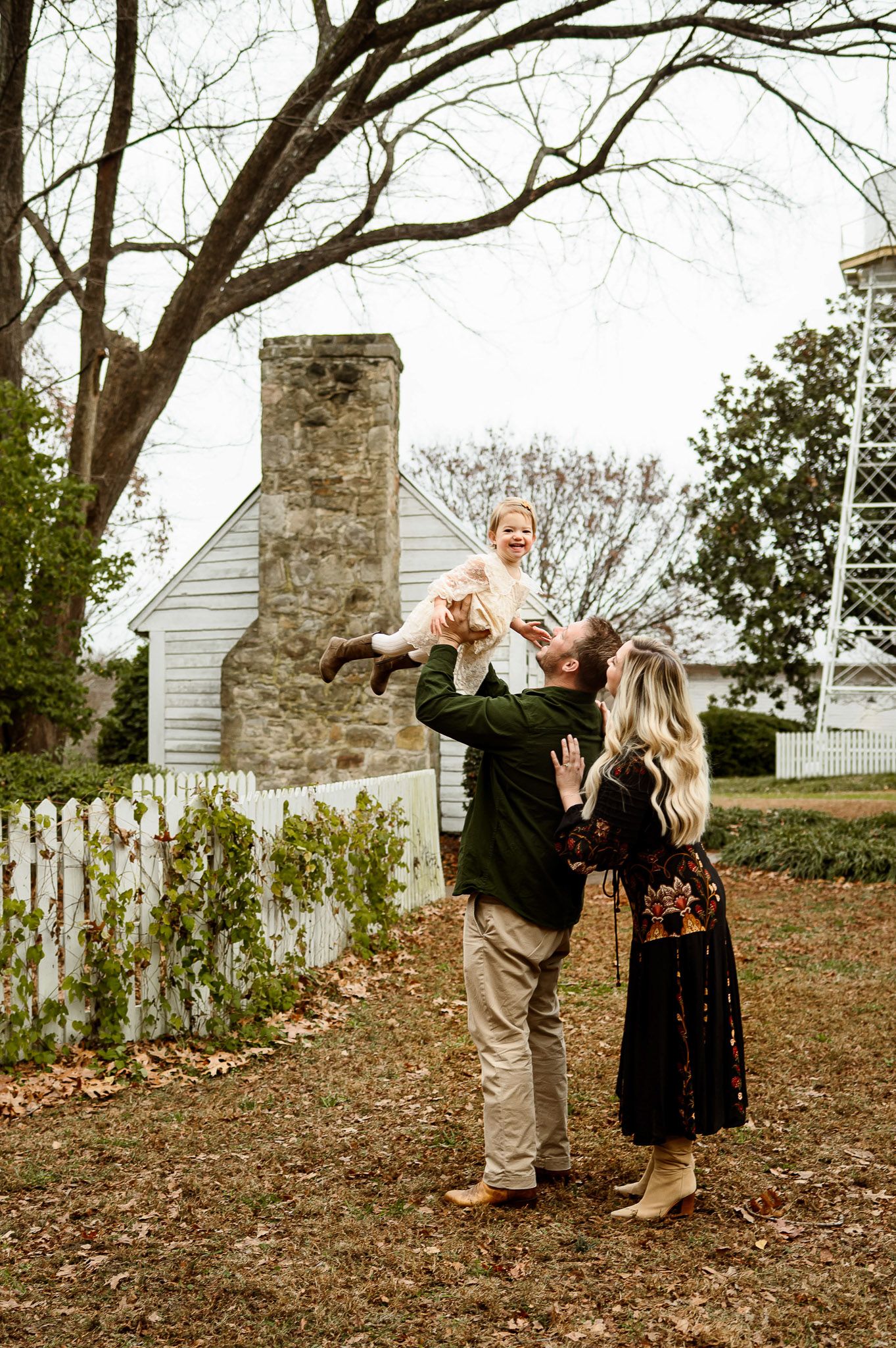 Parents lifting smiling toddler outdoors during playful family photography session in Raleigh NC