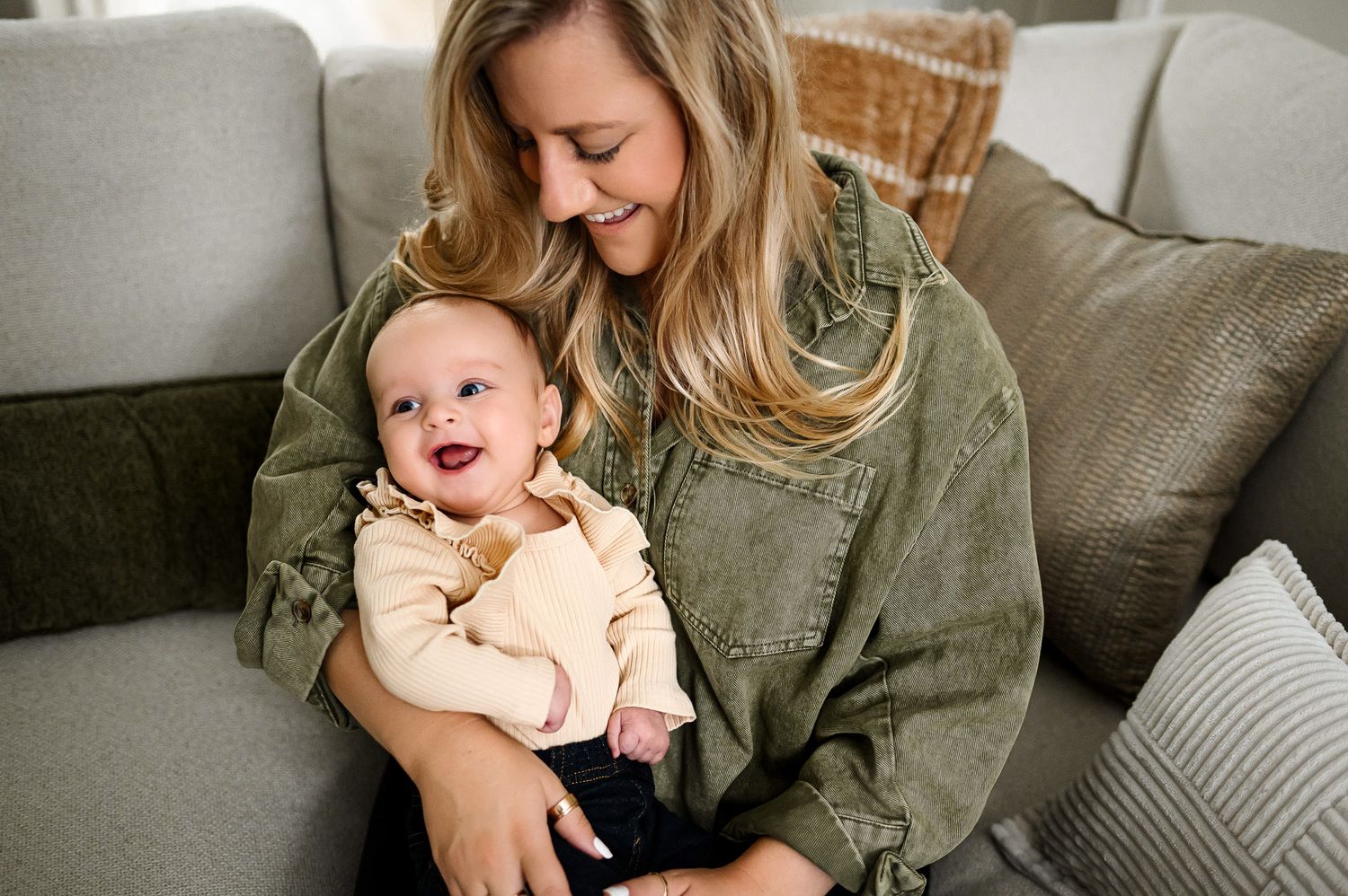 Mother holding her smiling baby on the couch during a relaxed in-home lifestyle family photography session