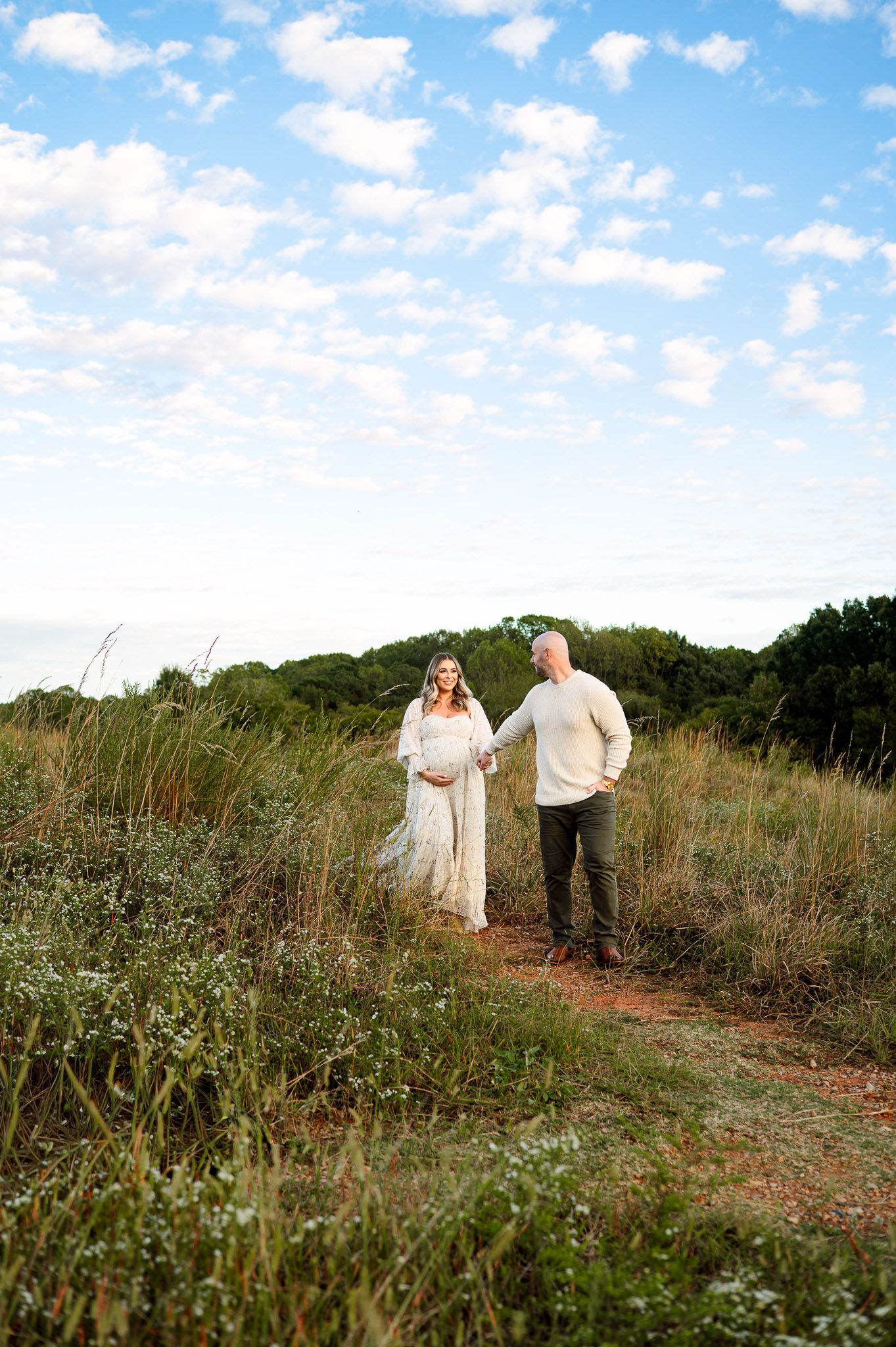 Expecting couple walking through a grassy field during a maternity photography session near Raleigh NC