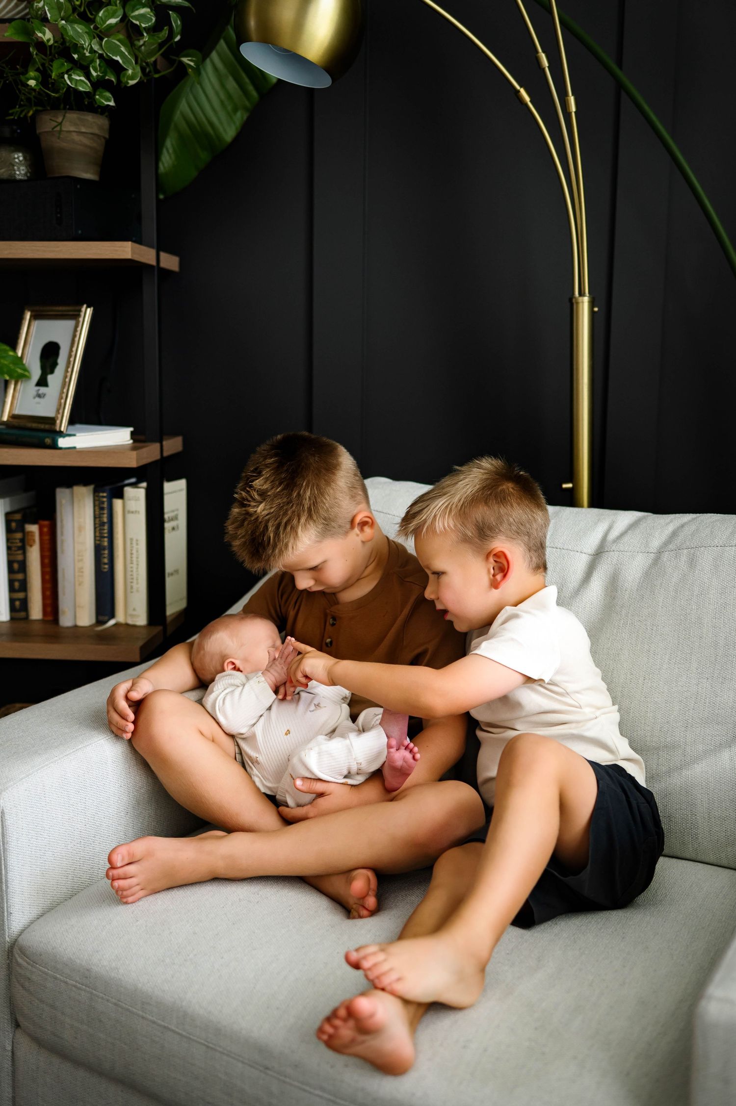 Raleigh newborn photographer captures two young siblings bonding with their baby brother during an in-home photo session