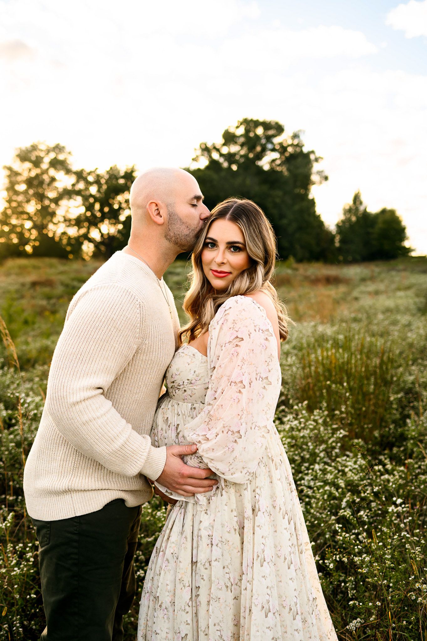 Expecting parents embracing during a golden hour maternity photography session in a field near Raleigh North Carolina