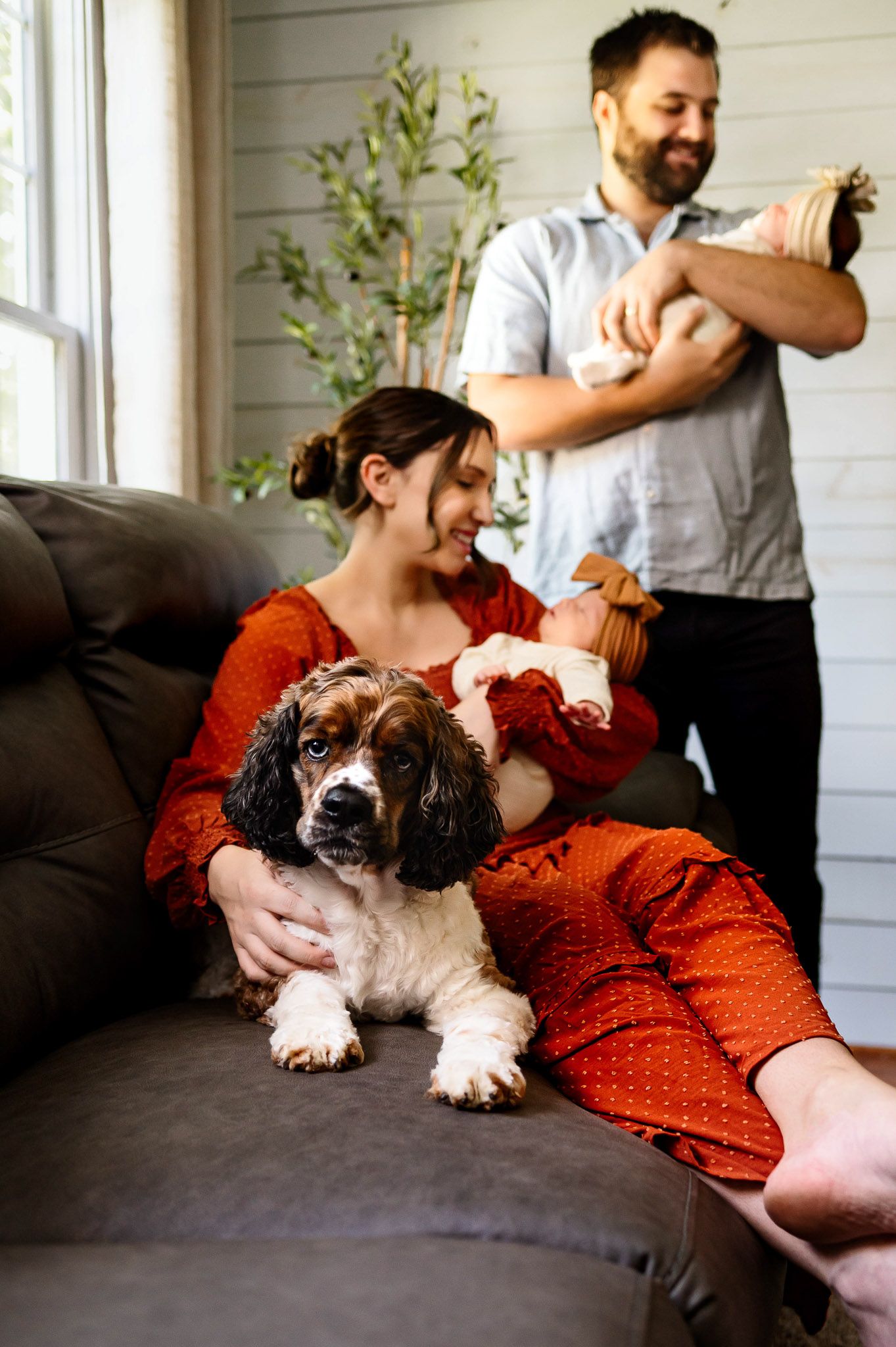 Parents relaxing with their newborn baby and family dog during an in-home lifestyle newborn photography session in Raleigh NC