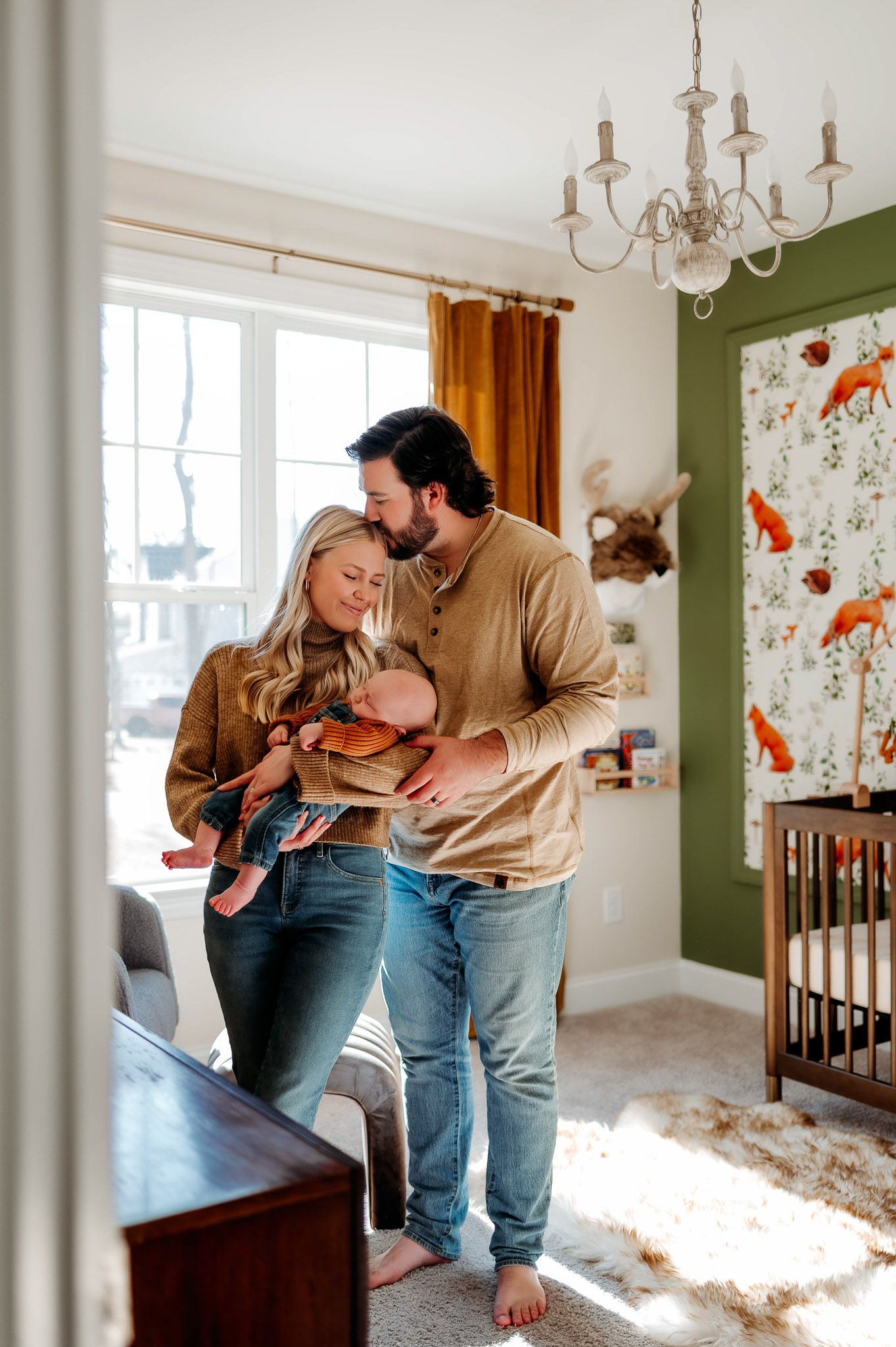 Parents holding their newborn baby together inside a nursery during a natural light lifestyle newborn session in Raleigh NC