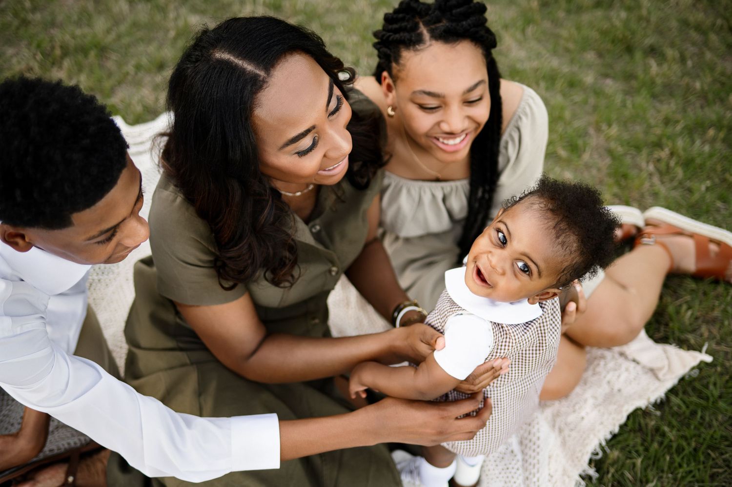 Raleigh family photographer captures candid photograph of mother sitting with her children while youngest child smiles up at camera