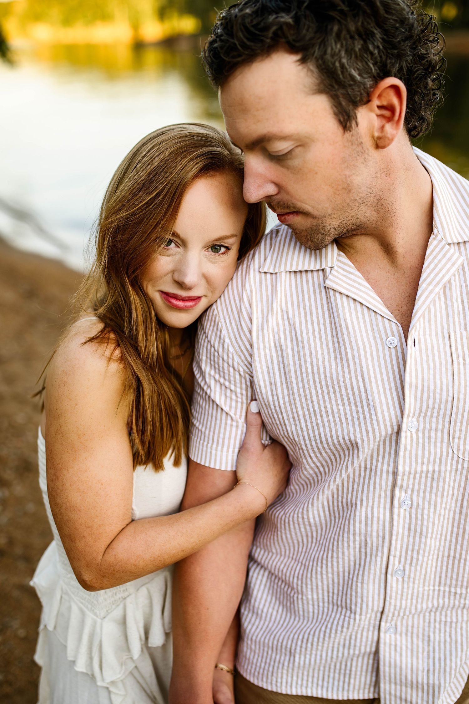 A romantic couple in casual attire shares tender moments outdoors during a golden hour photoshoot with Emma Branch Photography