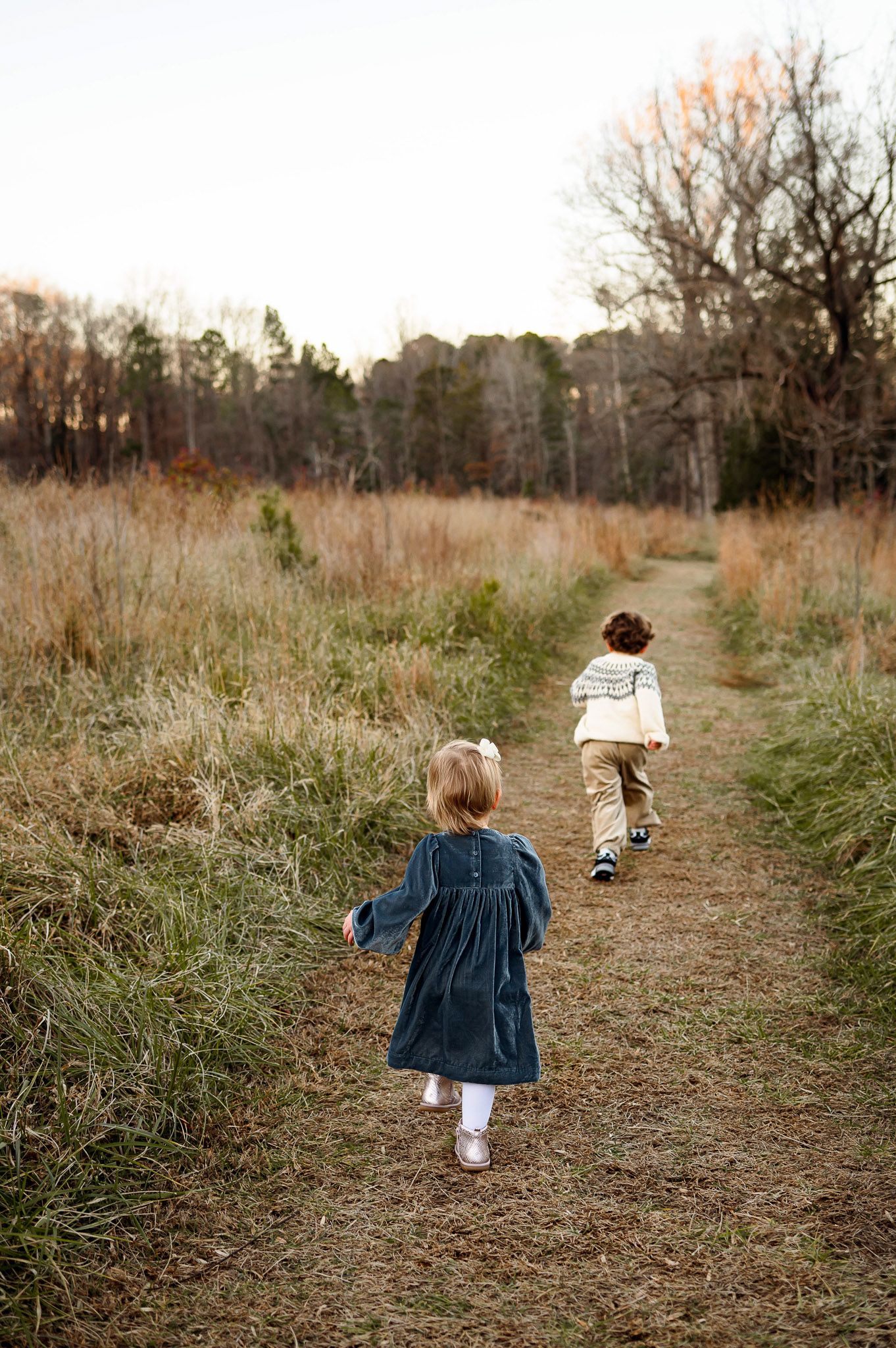 Two young siblings walking along a trail during a natural outdoor family photography session in Cary NC