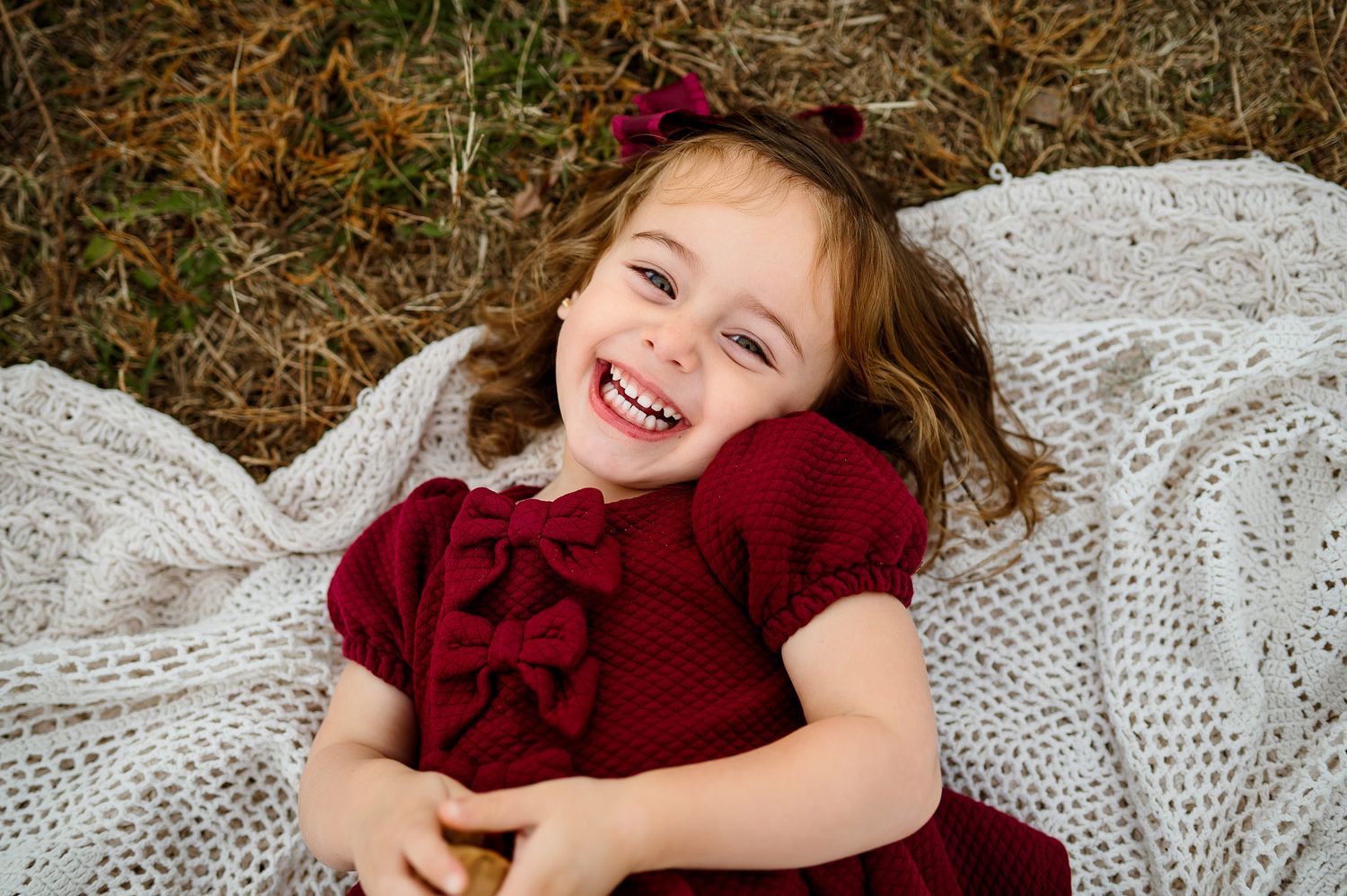 Smiling toddler lying on blanket during outdoor family photography session in Apex NC