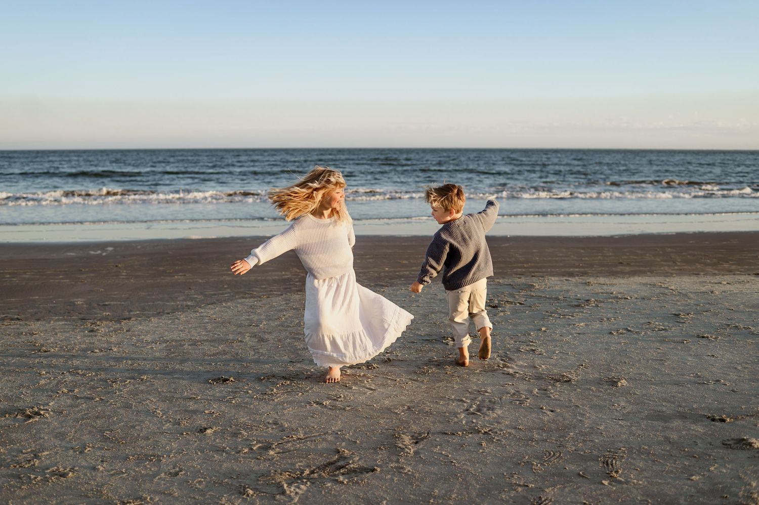Two children running and playing on beach during candid family photography session