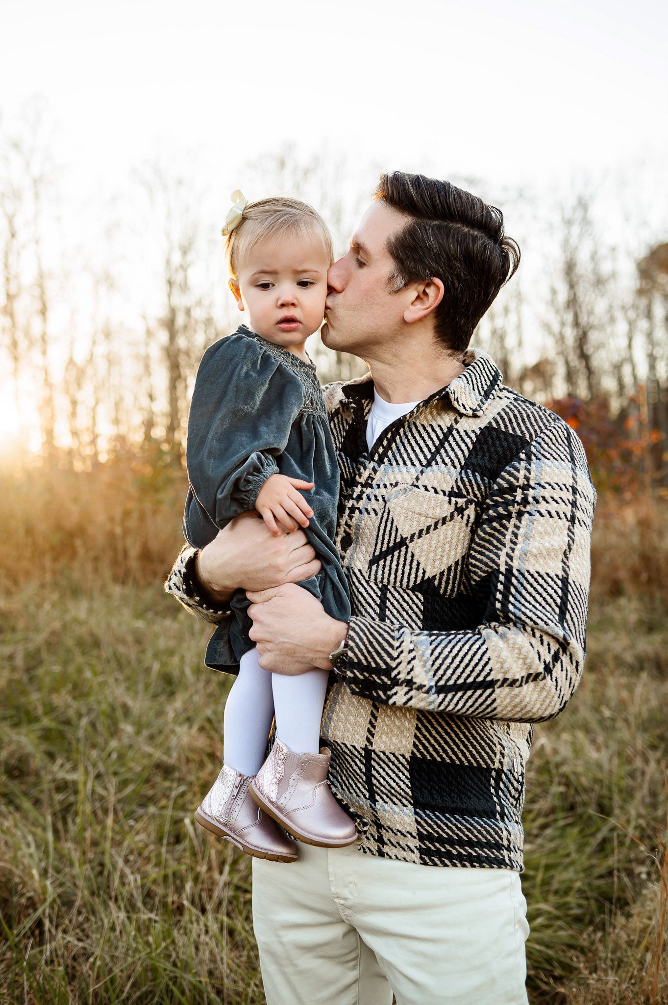 Father kissing his toddler daughter on the cheek during a golden hour family photography session in Raleigh NC