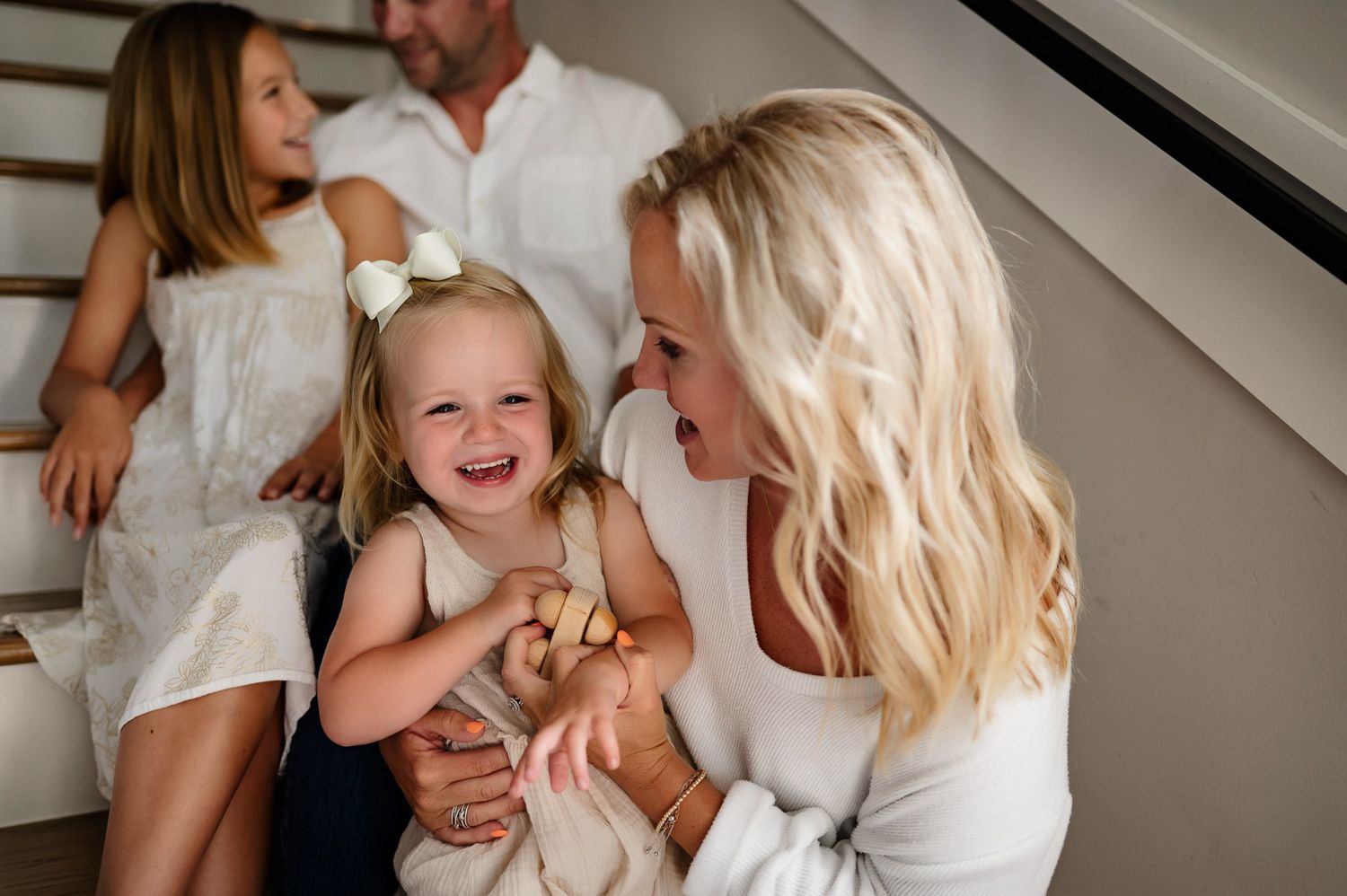 Mother laughing with her toddler daughter on the stairs during a candid in-home family photography session in Raleigh