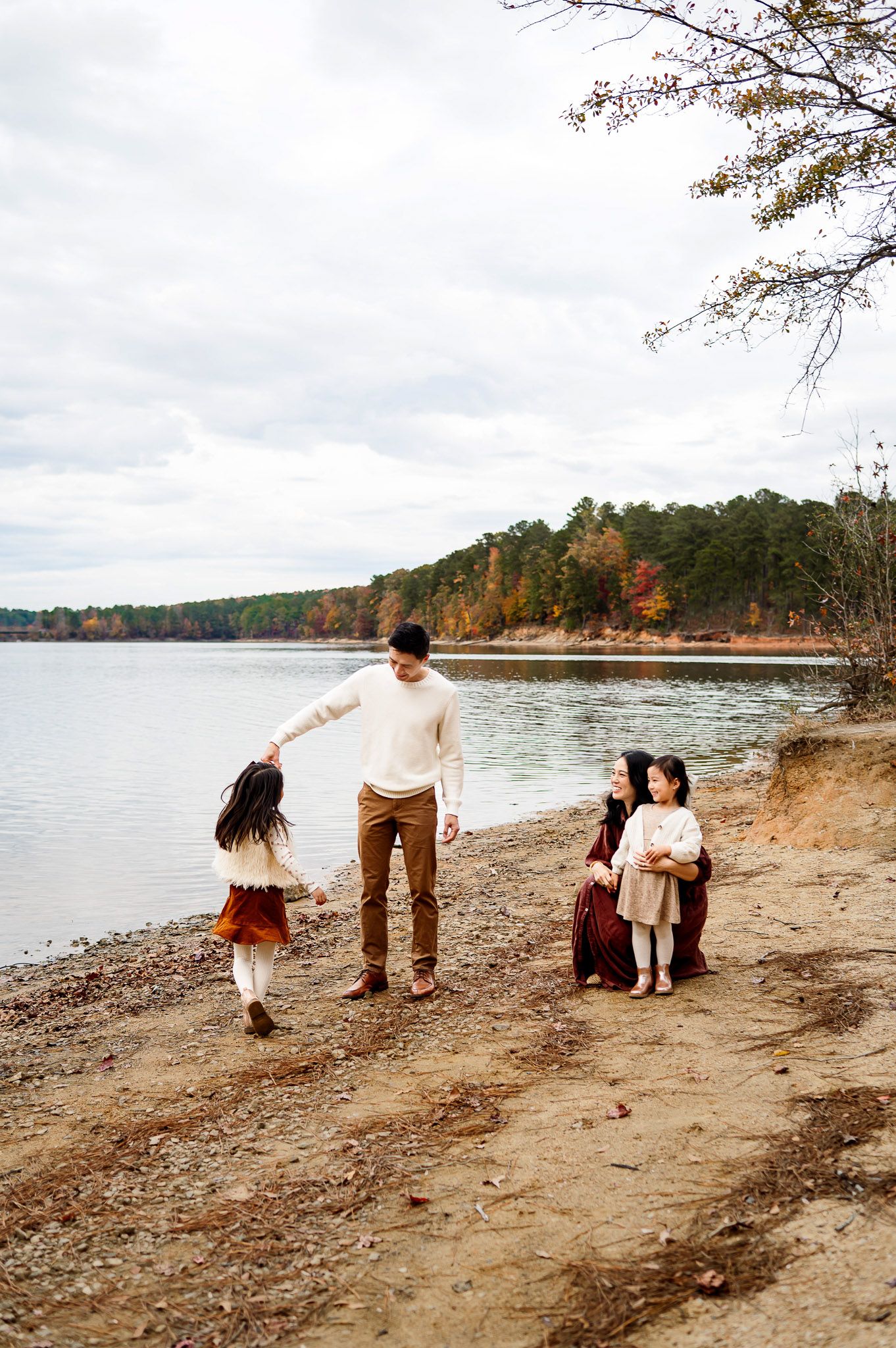 Father twirling his daughter while the rest of the family watches during a relaxed outdoor family photography session in Wake Forest NC