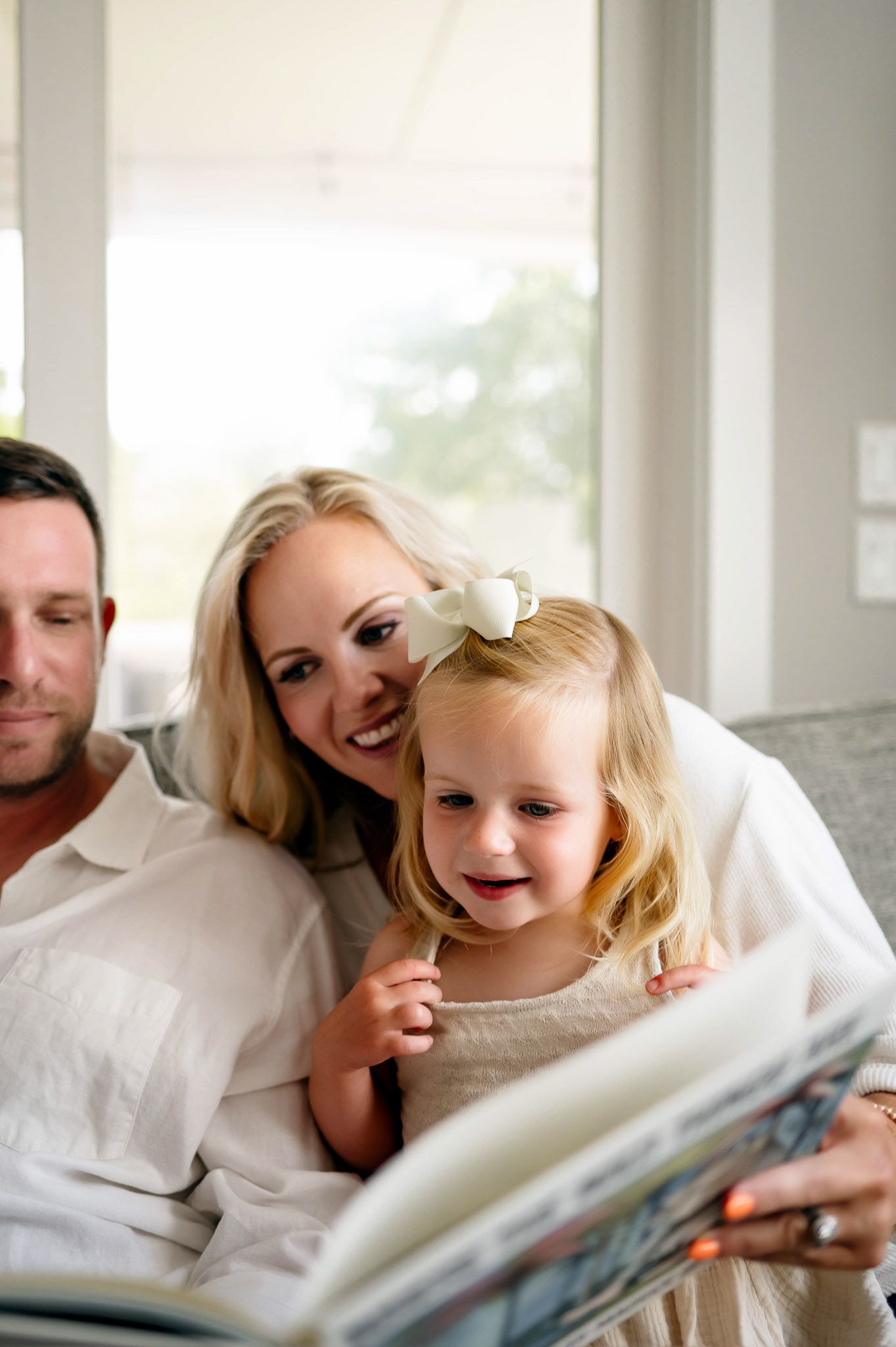 Mother and young daughter reading a book together during a cozy in-home family photography session Cary NC