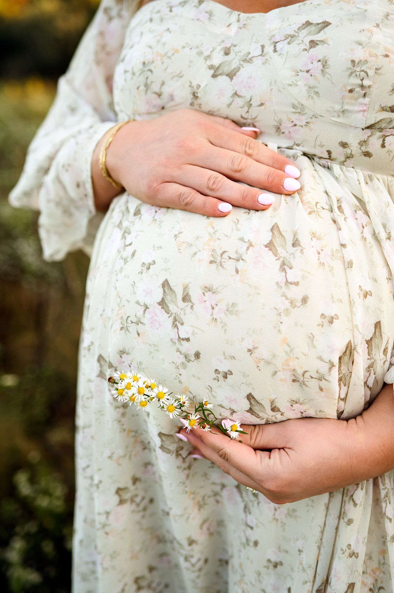 Close-up of a pregnant mother holding her baby bump during an outdoor maternity photography session in Raleigh NC